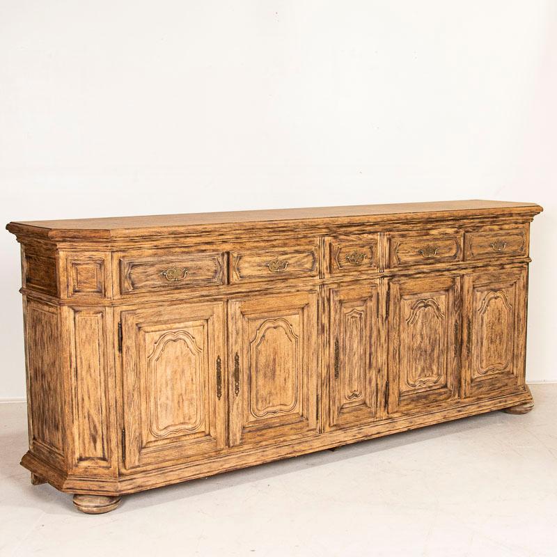 This impressive long sideboard shows off its French style in the traditionally carved panels of drawers, cabinet doors and canted sides which all accentuate the front. The 