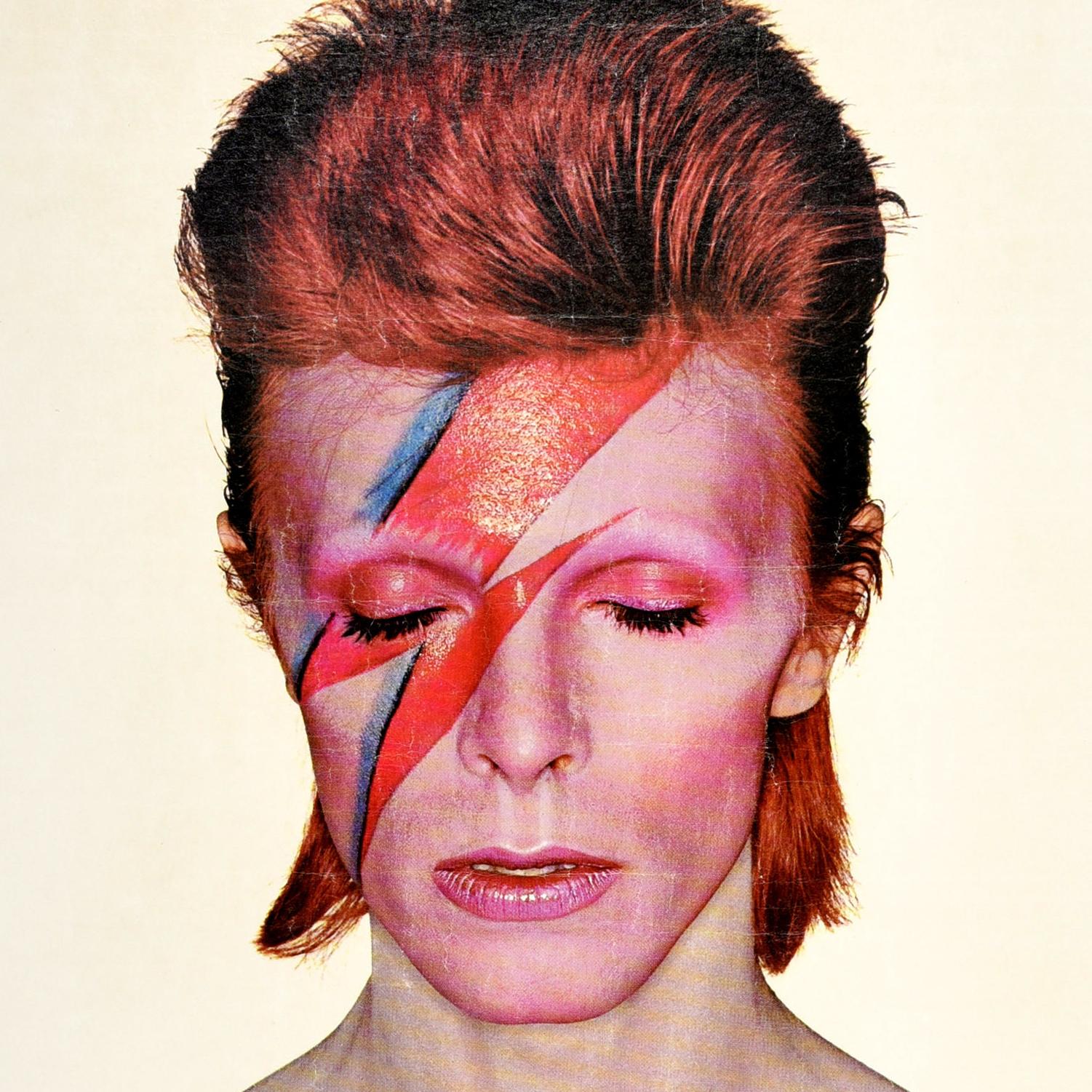 Original vintage music advertising poster for the David Bowie album Aladdin Sane released in 1973 featuring the iconic cover artwork by the English photographer Brian Duffy (1933-2010) of Bowie with red hair and his eyes closed, a red and blue
