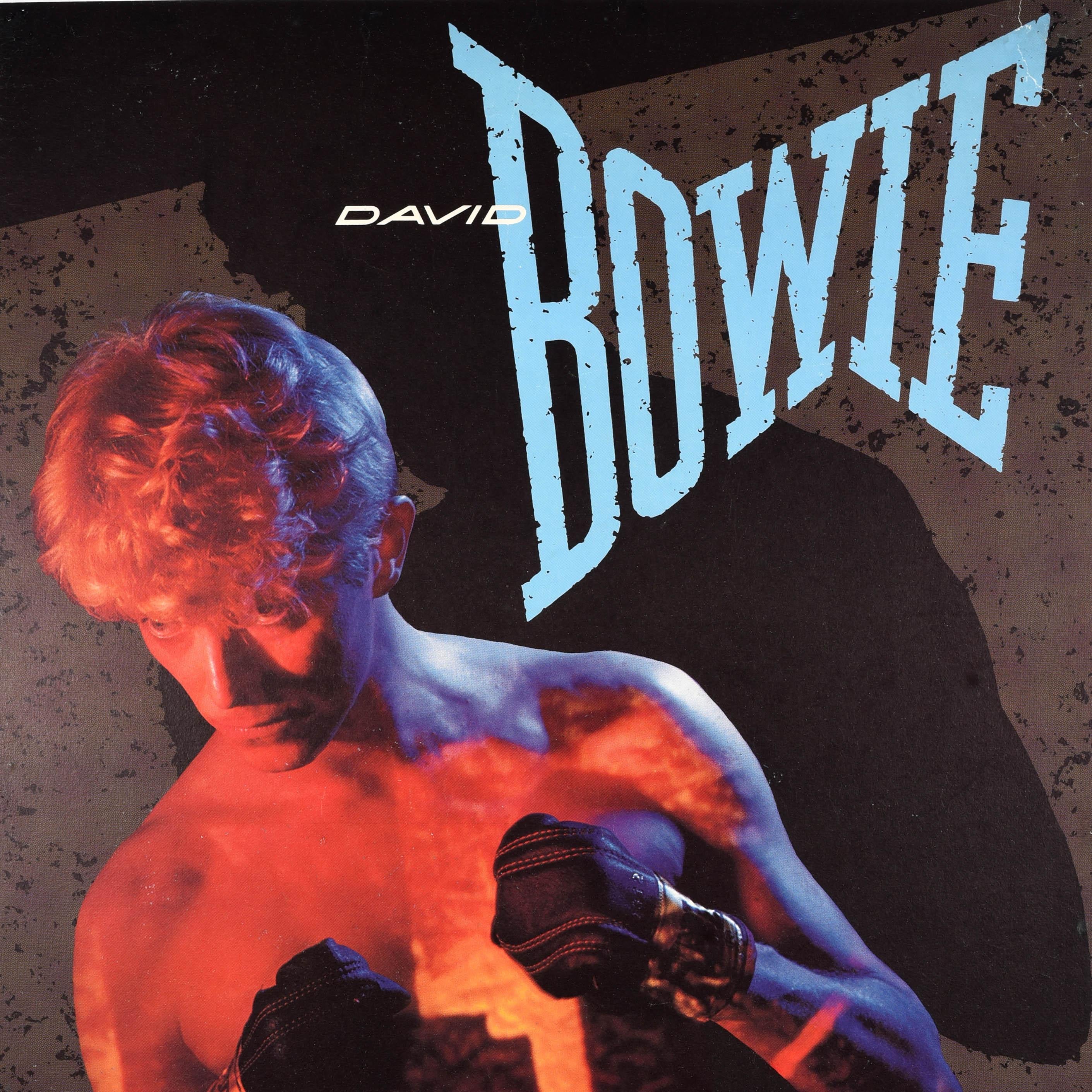 Poster pubblicitario musicale originale d'epoca per l'uscita americana del disco bestseller di David Bowie, Let's Dance, con il famoso design della copertina che raffigura il cantante e cantautore inglese David Bowie (1947-2016) che indossa guantoni