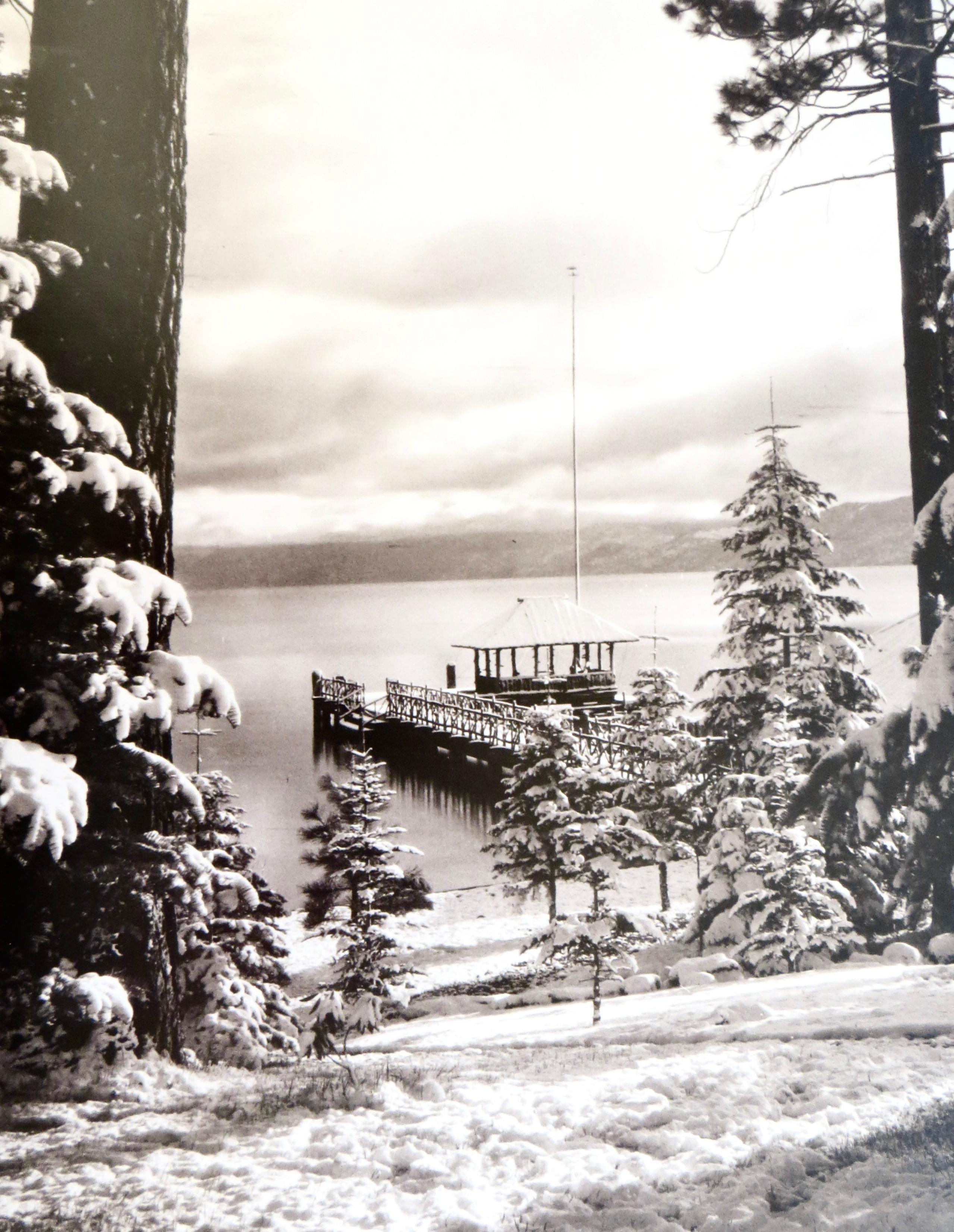 Das Vintage-Foto vom Lake Tahoe aus dem Jahr 1905 zeigt den See durch Bäume und Winterschnee. Typisch für die damalige Zeit ist der wünschenswerte leichte Sepiaton des Abzugs, der vom Originalnegativ erstellt wurde (siehe Abbildungen). Das Bild ist