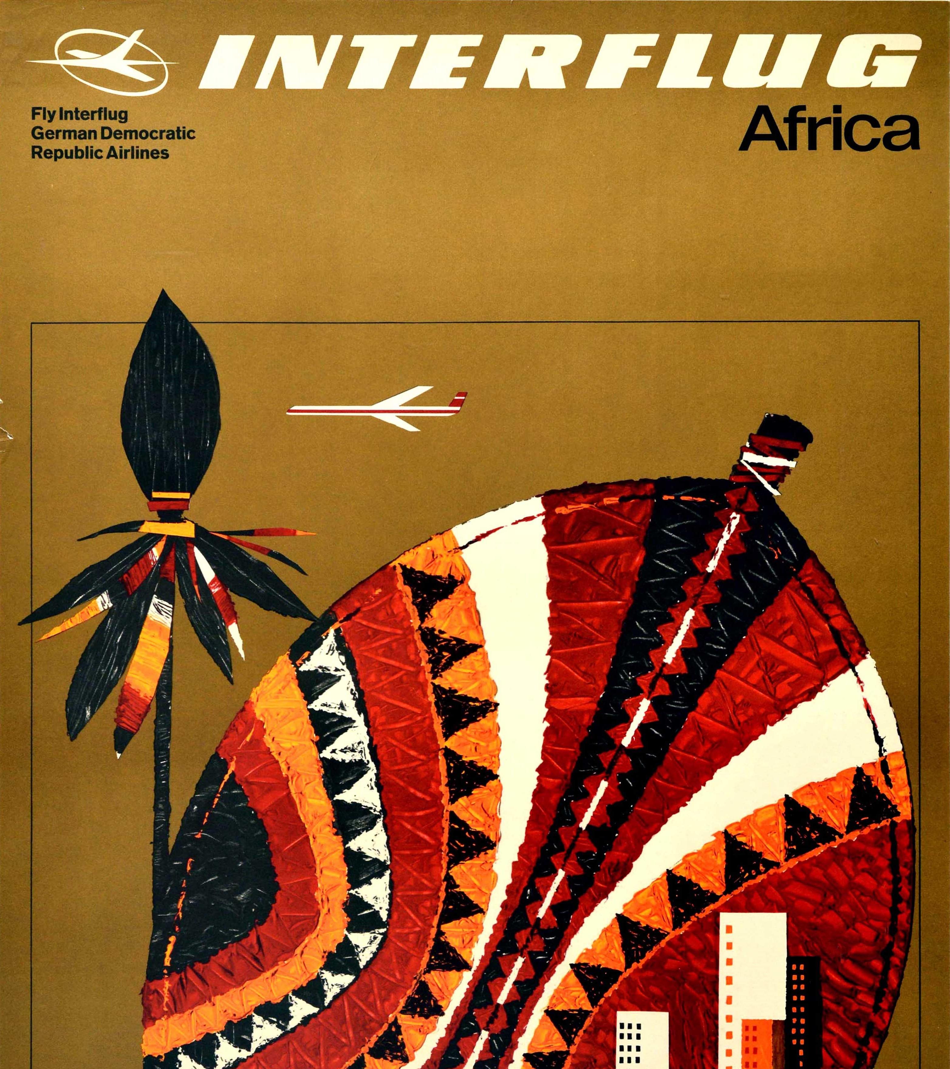 Original vintage aviation advertising poster for Interflug Africa - Fly Interflug German Democratic Republic Airlines - featuring a stylised white and red plane flying over a spear and shield decorated in a traditional colourful pattern with an