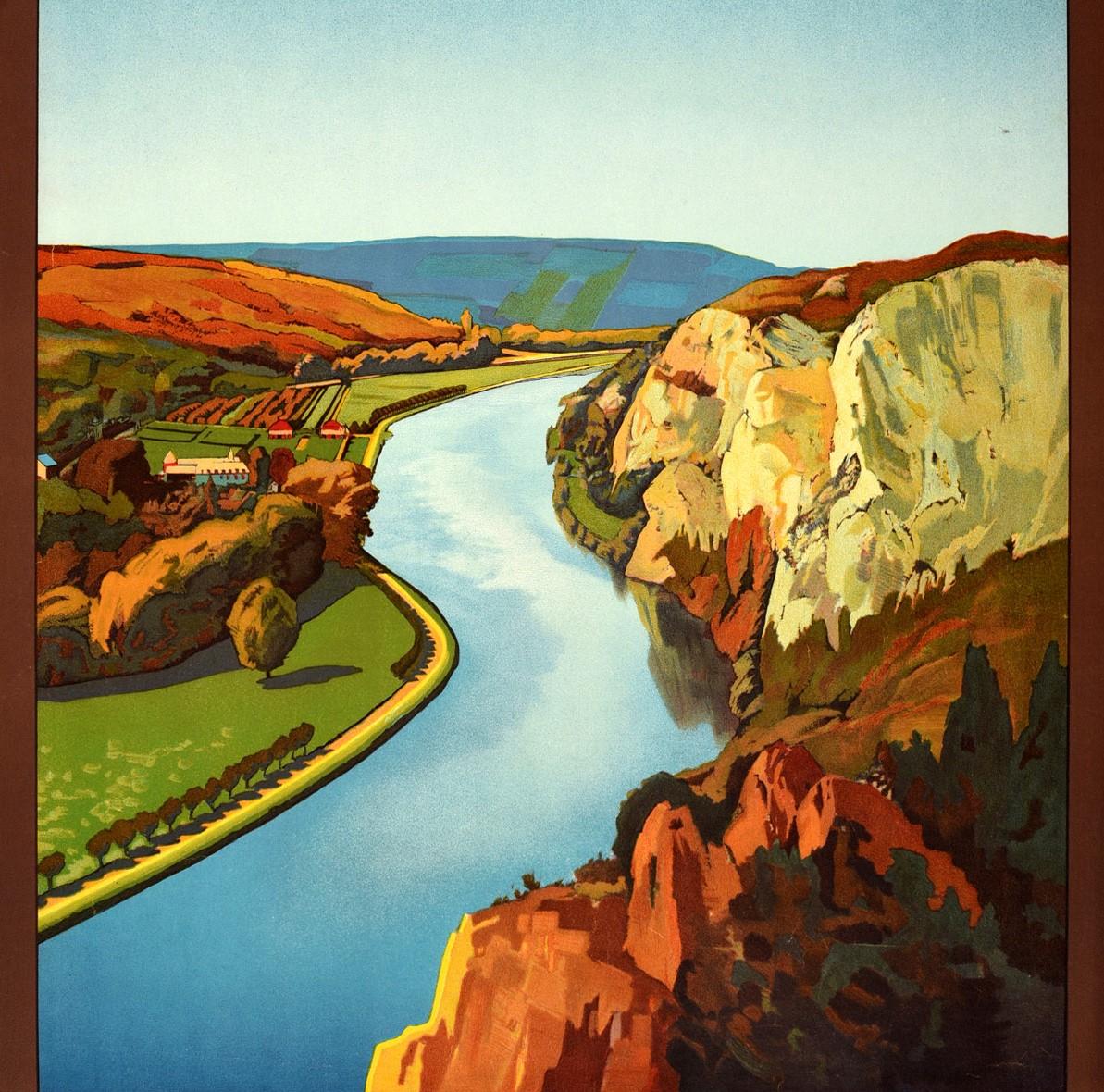 Original vintage travel poster for Belgium The Valley of the Meuse Its Wonderful Touristic Centres featuring colourful artwork depicting a scenic view of a river reflecting the cliffs on the calm water with trees, buildings and fields leading