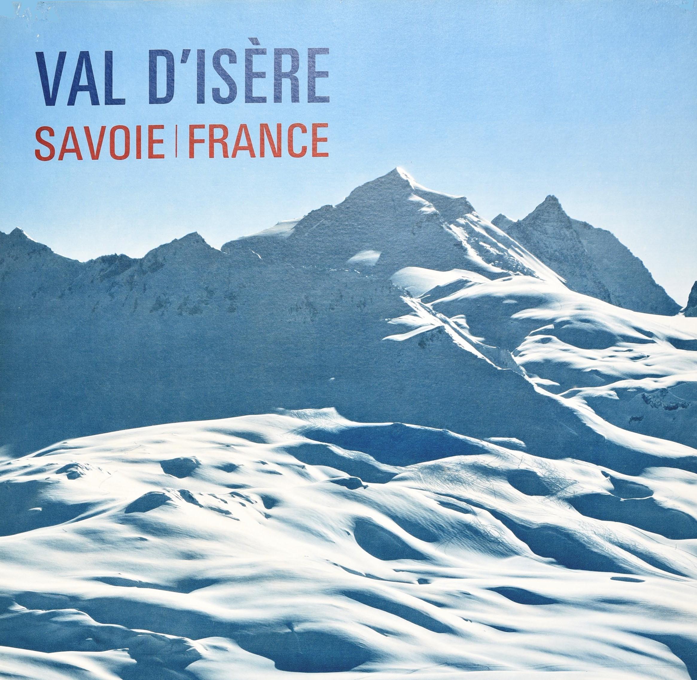 Affiche originale de voyage de ski vintage pour Val d'Isère, Savoie, France, présentant une vue panoramique de skieurs dévalant une piste avec des pics montagneux enneigés sous le ciel bleu et le texte du titre bleu et rouge. Bon état, déchirures