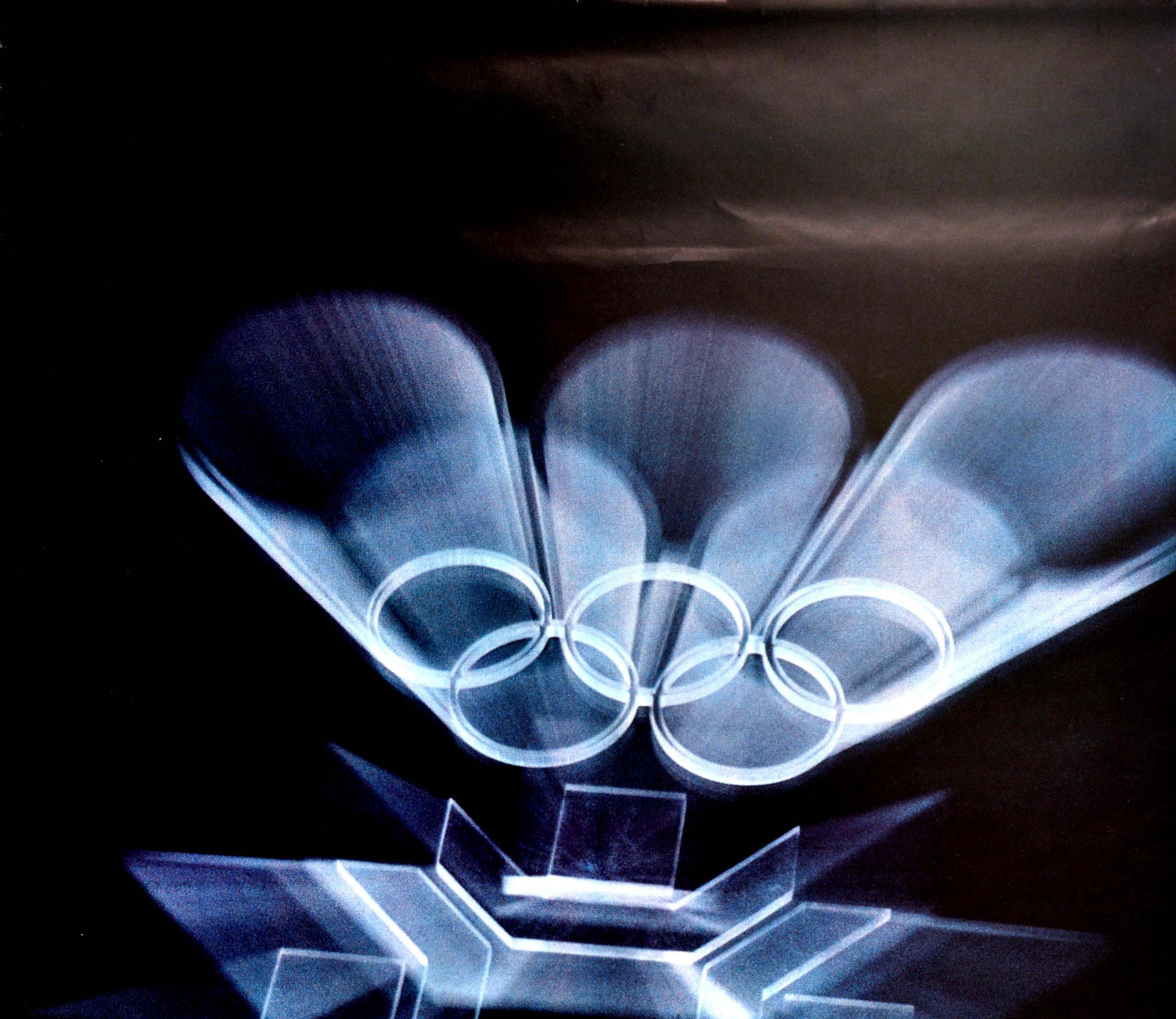 Original vintage winter sports poster for the XIV Olympic Winter Games Sarajevo 1984 Yugoslavia featuring a dynamic design of the Olympic Rings and 1984 Winter Olympics logo in silver shining on a black background, the emblem symbolising a stylised