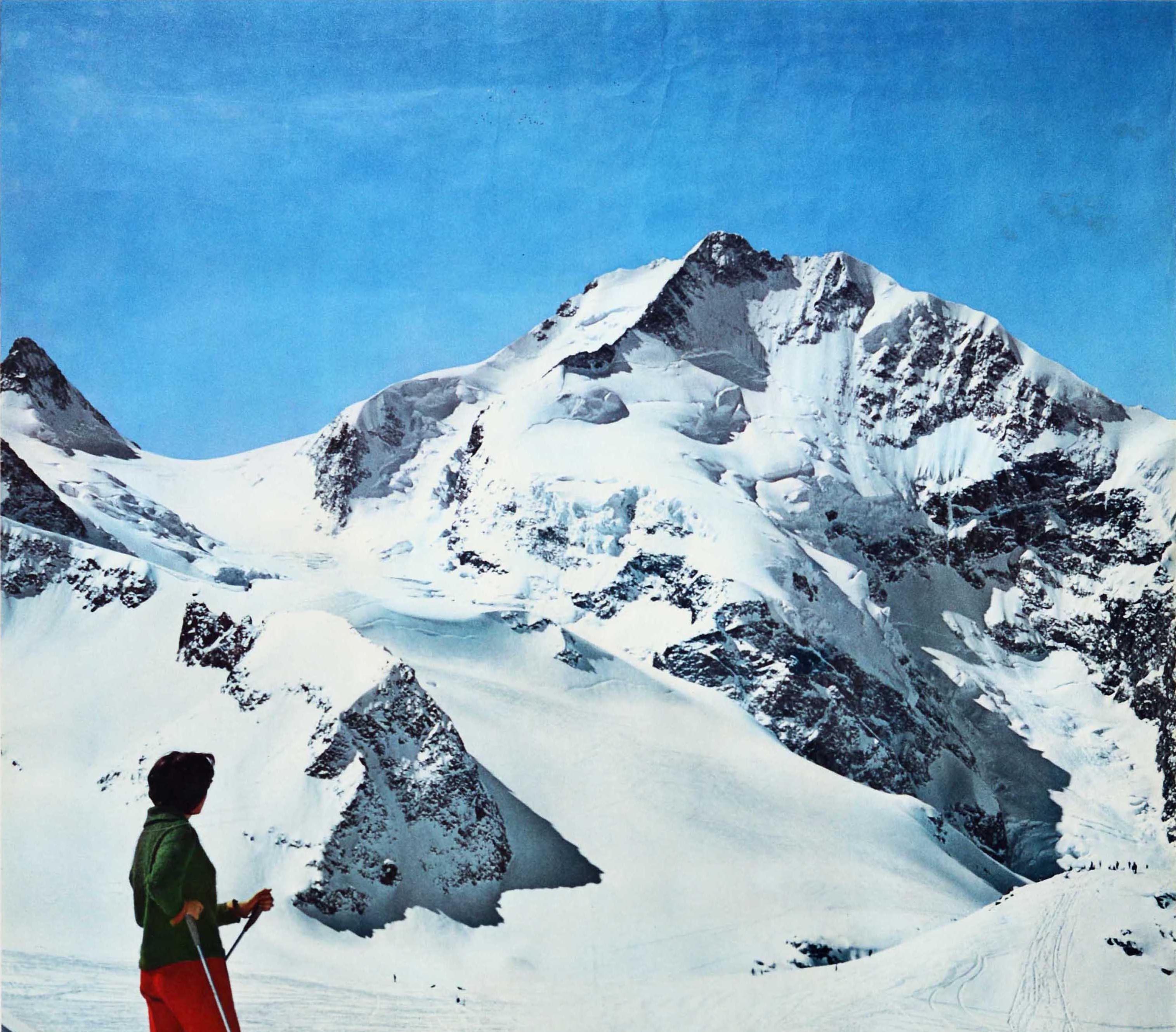 Original vintage winter sport ski poster for the popular Swiss resort of Pontresina featuring a photograph of a lady on skis standing on a mountain and admiring the beauty of the Engadin Alps with a ski lift and skiers on the piste below, the title