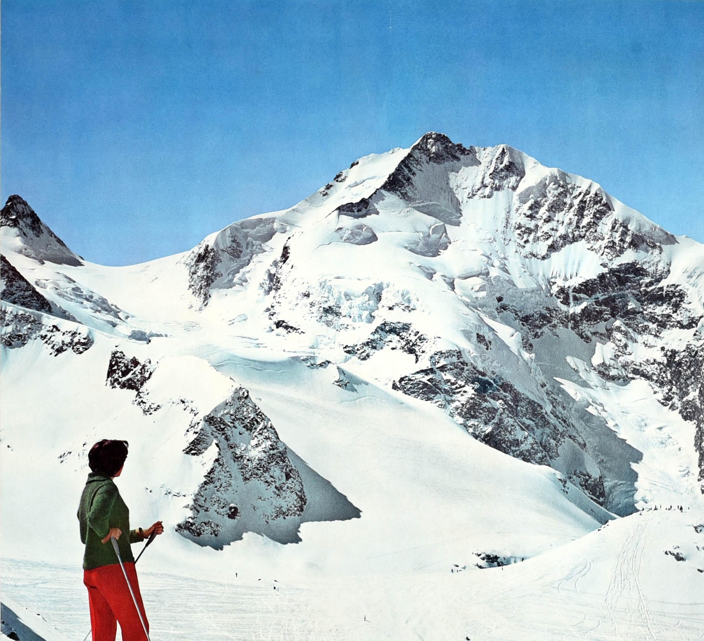Original vintage winter sport ski poster for the popular Swiss resort of Pontresina featuring a photograph of a lady on skis standing on a mountain and admiring the beauty of the Engadin Alps with a ski lift and skiers on the piste below, the title