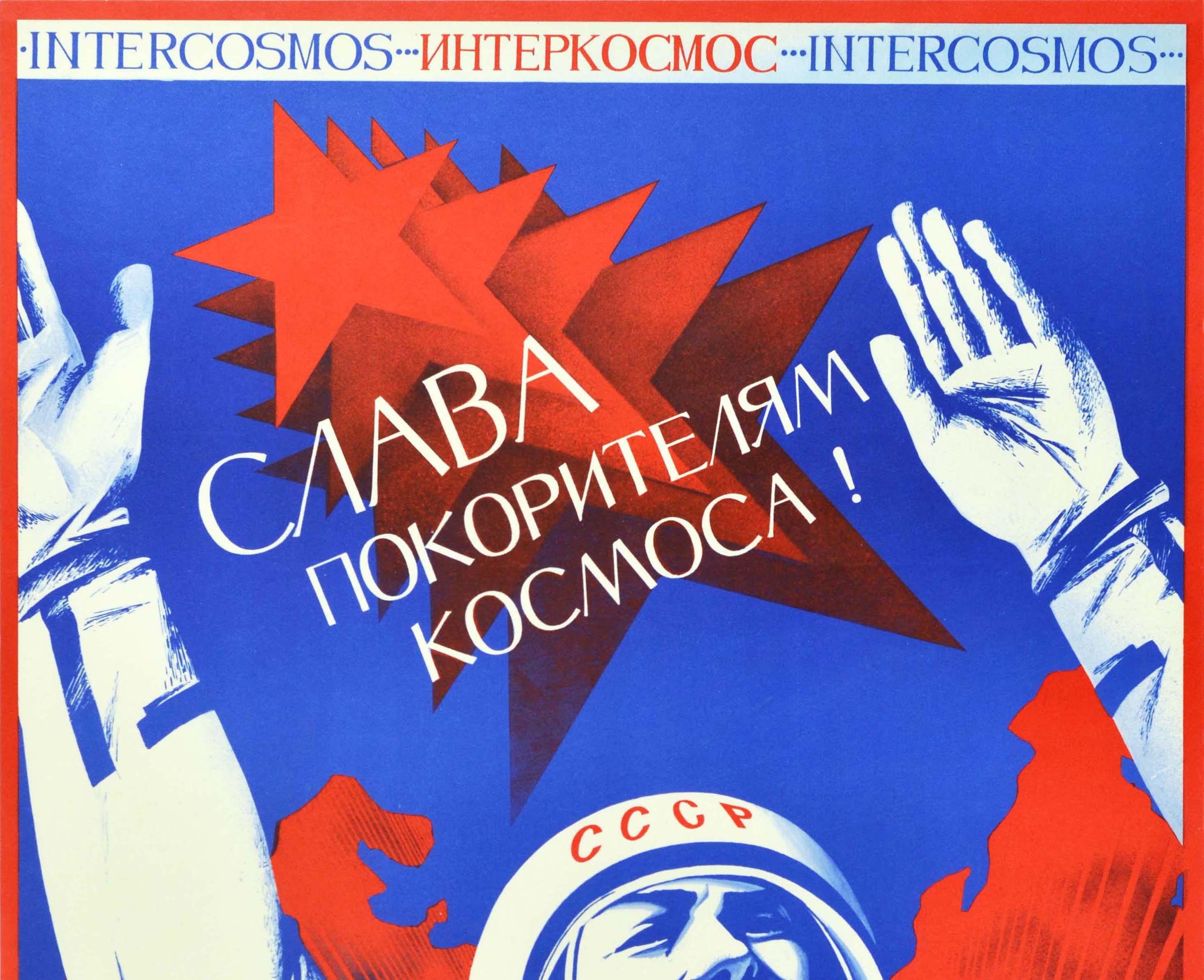 Original vintage Soviet space poster - Interkosmos Glory to the conquerors of space! / ??????????? ????? ??????????? ???????! - featuring a cosmonaut in a suit holding up his hands in celebration in front of a map of the Soviet Union in red on the
