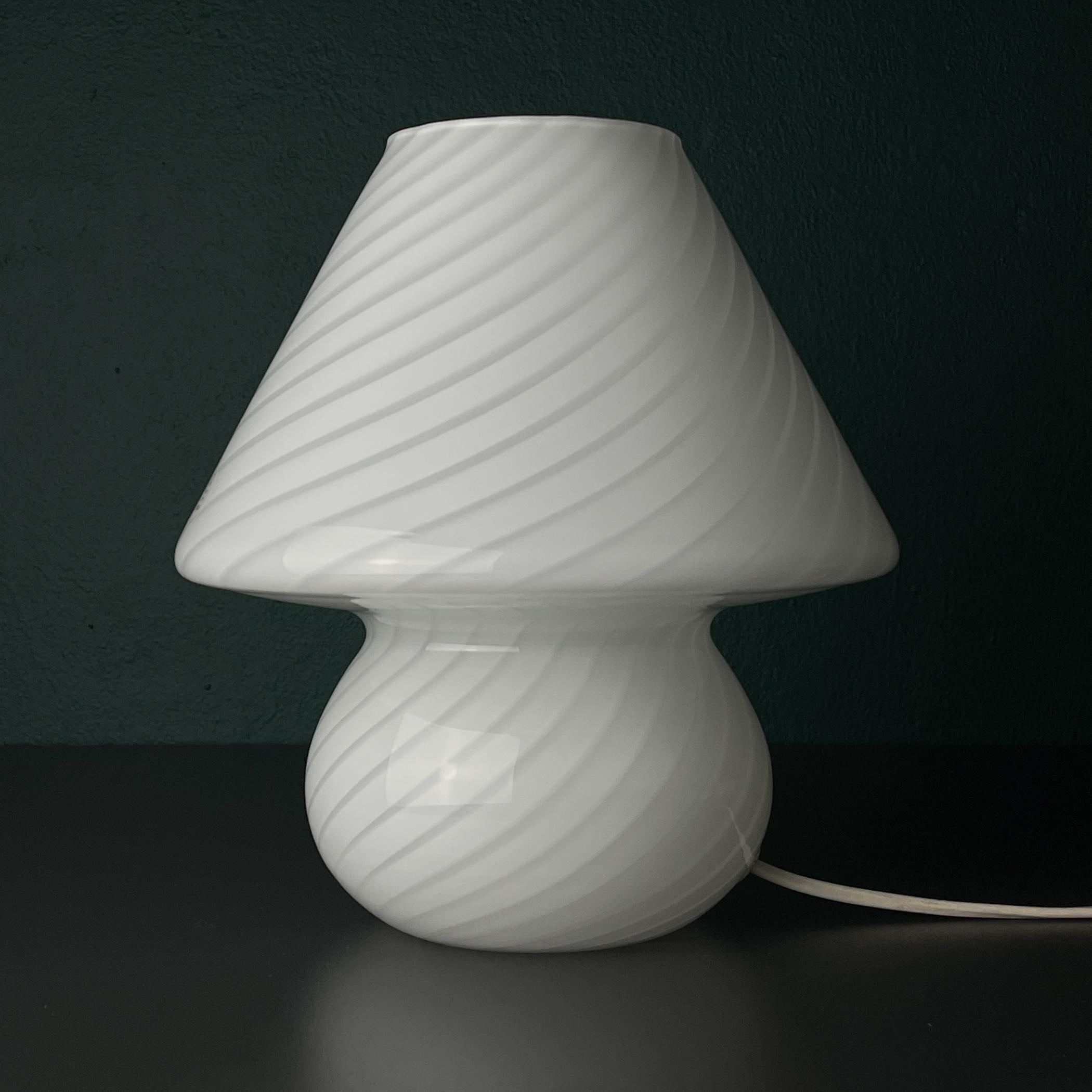 Un classico del design italiano: la lampada da tavolo a forma di fungo. Realizzato in vetro di Murano di colore bianco latte negli anni '70. Originale lampada vintage realizzata a mano in Italia.

La lampada ha l'etichetta originale del