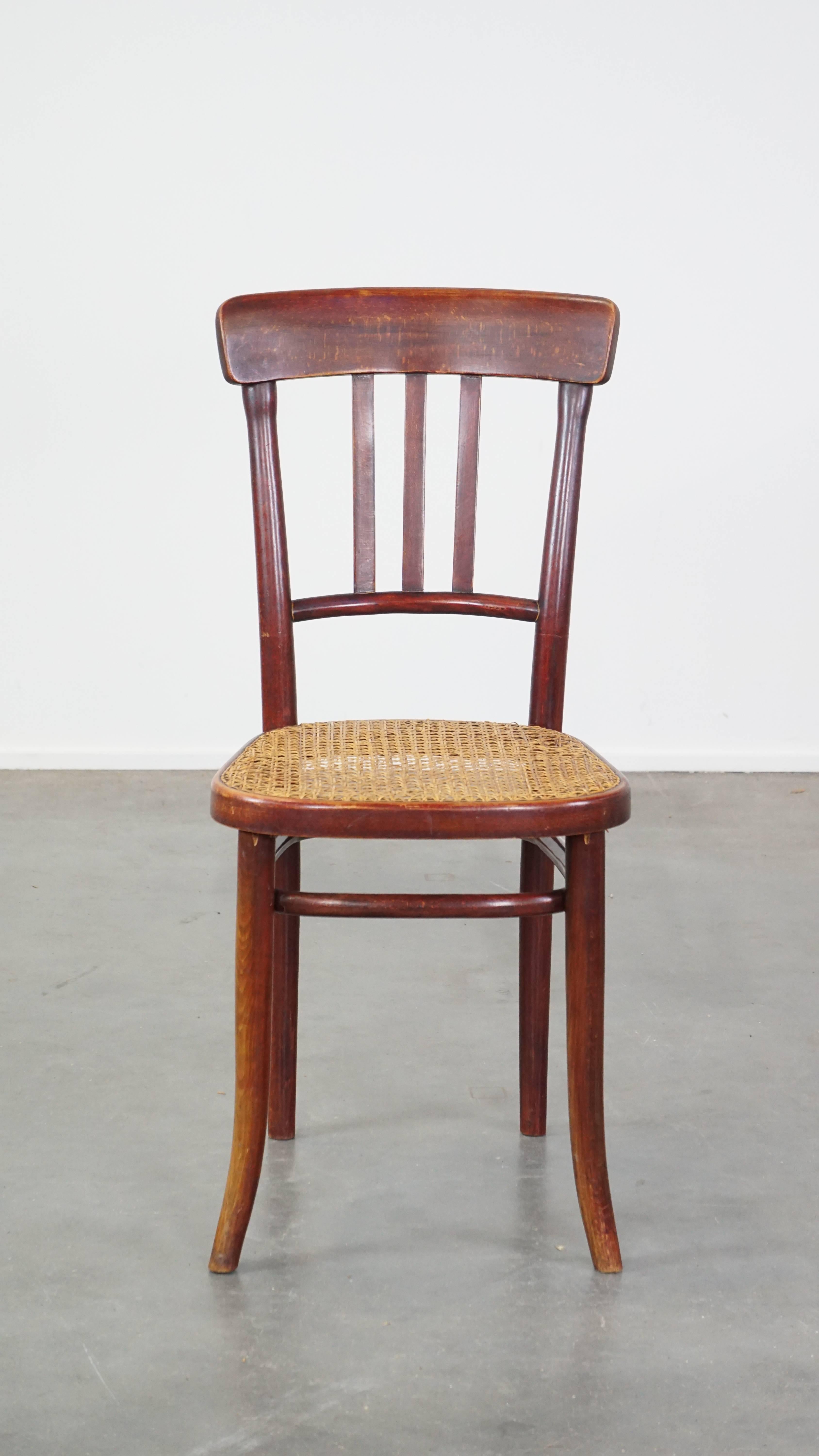 This amazing vintage Thonet design chair fits easily into almost any interior. This timeless chair looks great at both classic and modern dining tables. It is made of wood, has a rattan matte seat, and is labeled with the Thonet logo on the