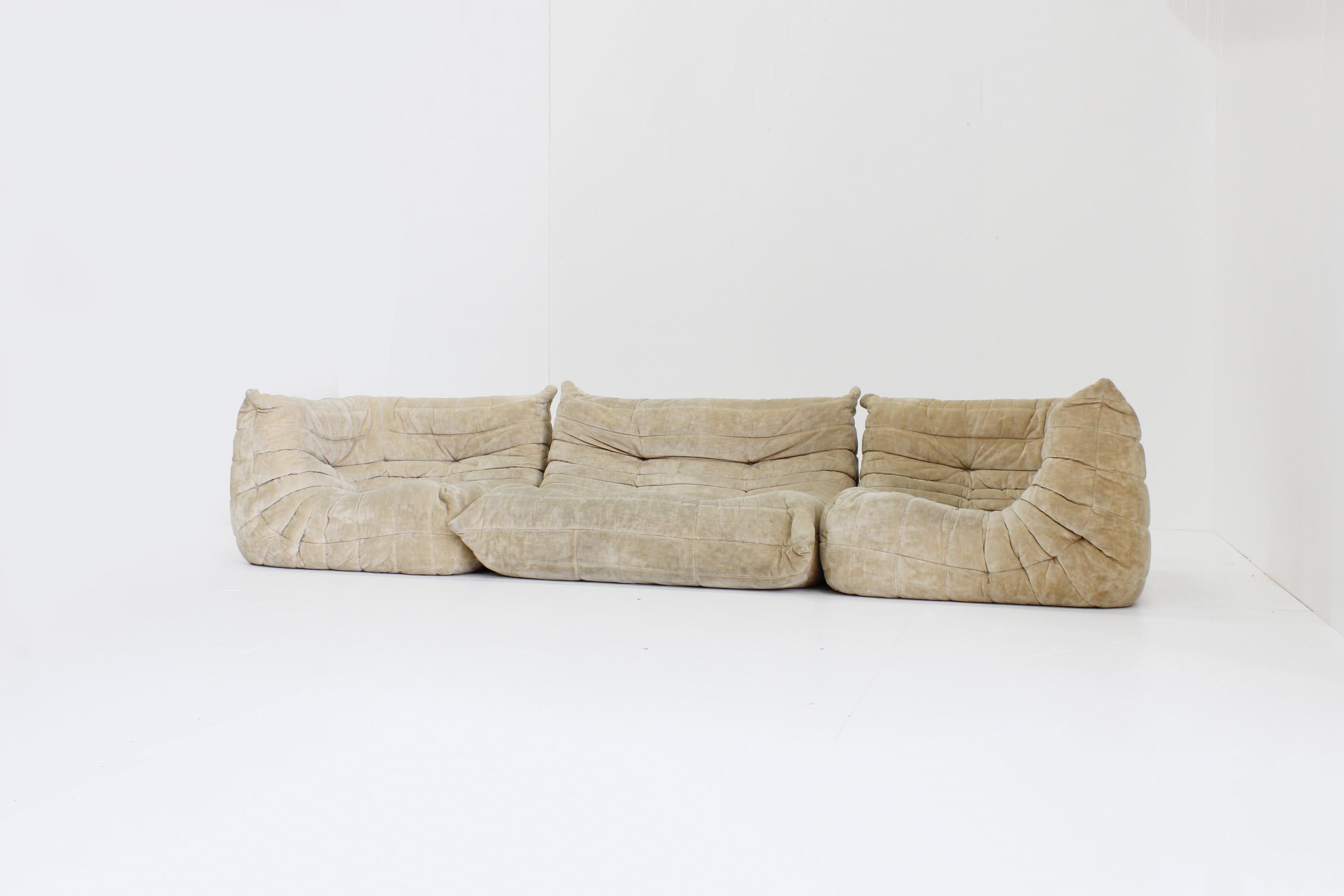 Original vintage Togo sofa set by Ligne Roset designed by Michel Ducaroy. This is an original set consisting of a 2 seater sofa and 2 corner pieces in beige velvet fabric.
 
The sofa is made in 1983 by Ligne Roset with a design of Michel Ducaroy.