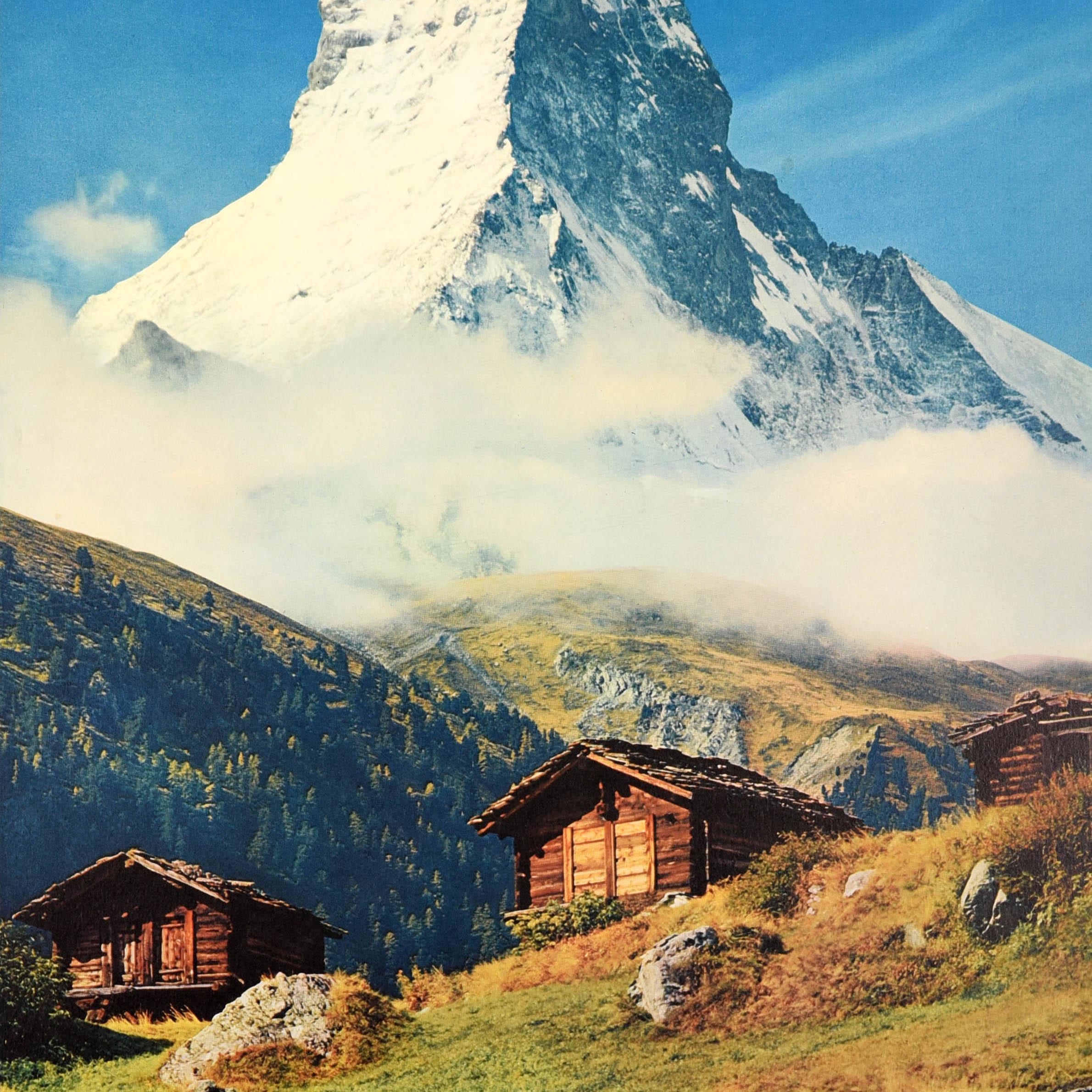 Original vintage travel poster for Zermatt Schweiz Suisse Switzerland featuring a scenic view looking up towards the snow topped Matterhorn mountain (Cervin) through a thin layer of cloud with wooden chalets and rocks on a hillside field below.