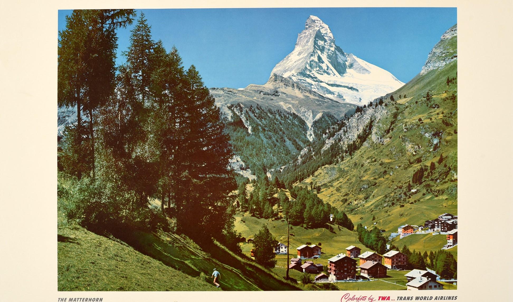 Original vintage airline travel poster - Along the way of TWA... Switzerland The Matterhorn - featuring a photograph of trees on a green hill with a small town nestled in the valley overlooked by the snow topped Matterhorn mountain in the distance