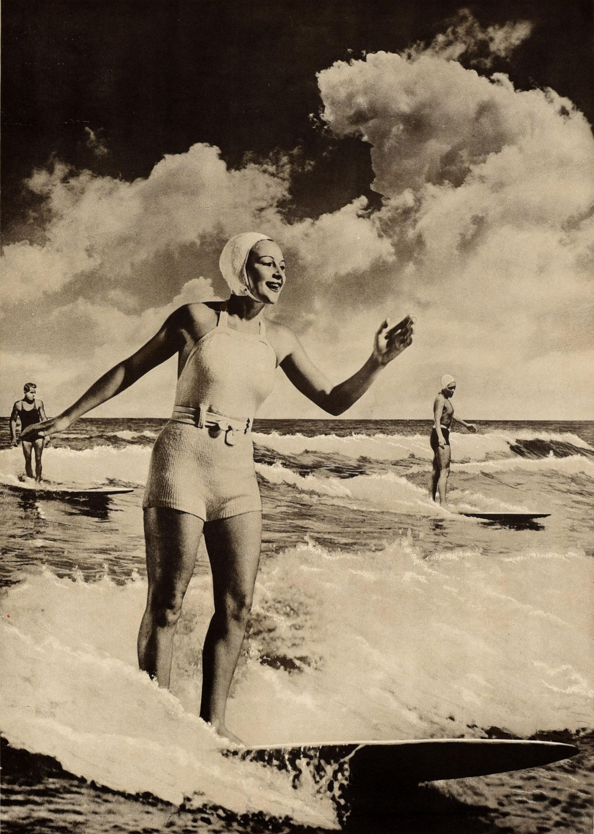 Original Vintage Sport thematische Reiseplakat - Surfen Australien - mit einem Schwarz-Weiß-Foto von einer lächelnden Dame in einem Badeanzug und Kappe Surfen auf einer Welle mit zwei Männern auf Surfbrettern im Meer im Hintergrund, das Bild in