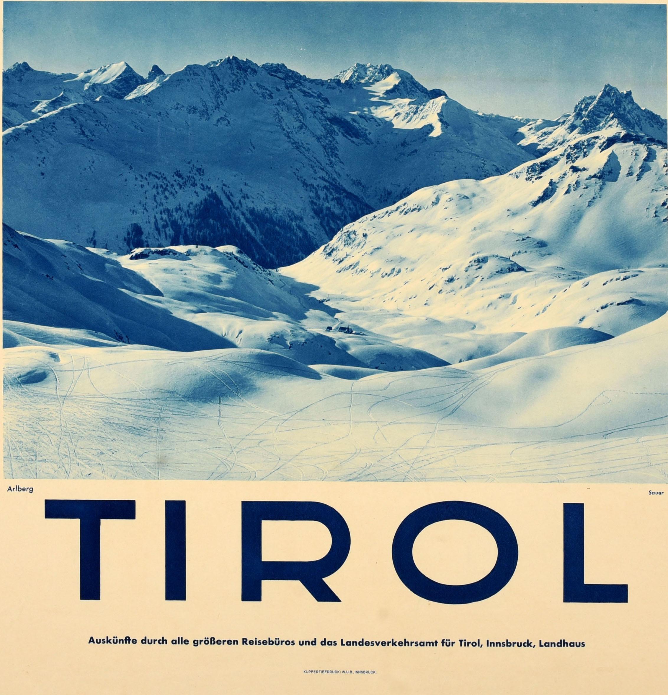 Originale poster d'epoca per gli sport invernali e lo sci in Tirolo, con una panoramica fotografia a tinte blu della catena montuosa dell'Arlberg ricoperta di neve, con le piste da sci sulle piste e la scritta in grassetto sul bordo sottostante.