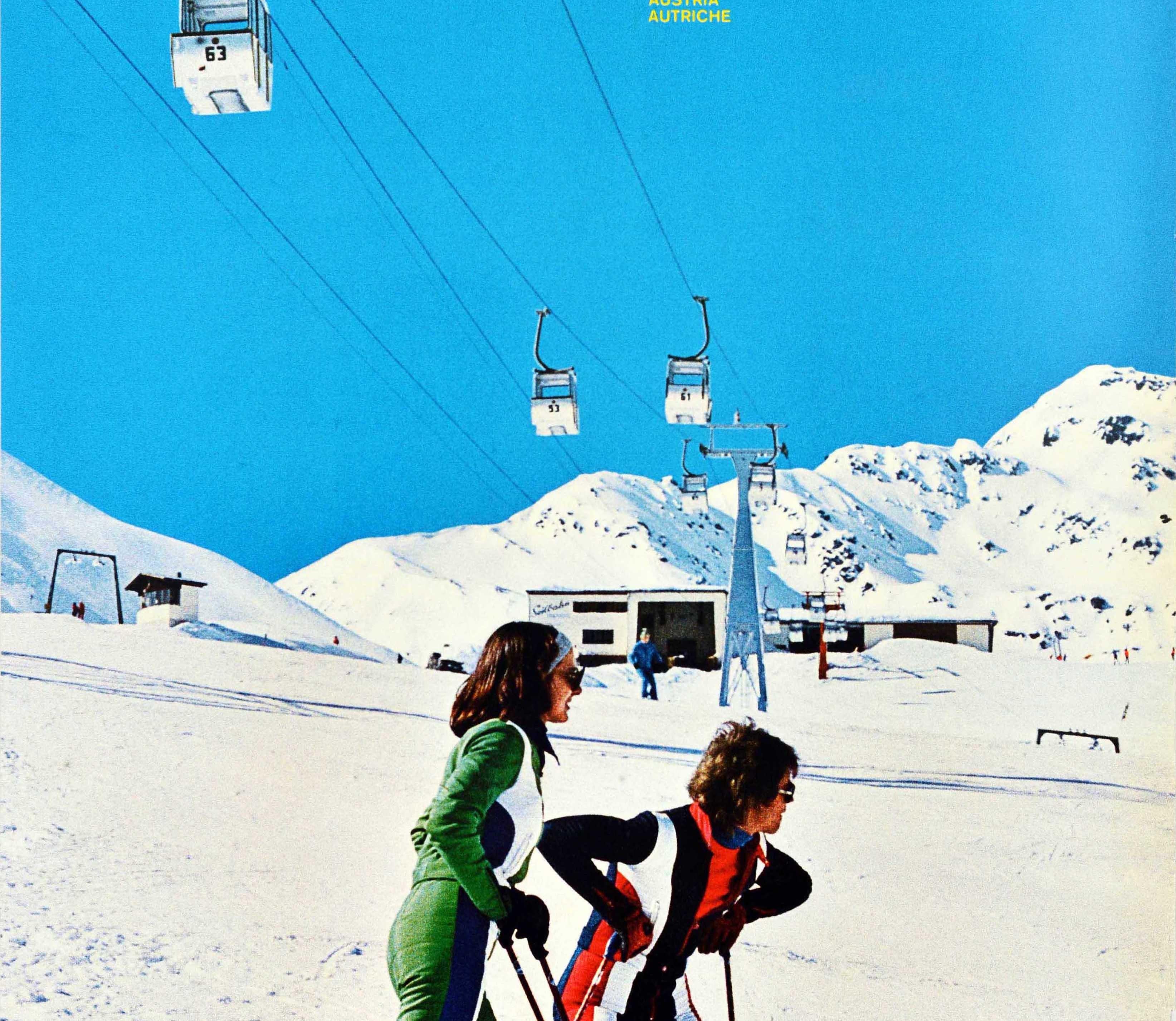 Original vintage winter travel poster for Tirol Osterreich Austria Autriche featuring a photograph of skiers in fashionable ski suits on a piste with a ski lift running above them, the stylised outline title lettering in yellow against the blue sky