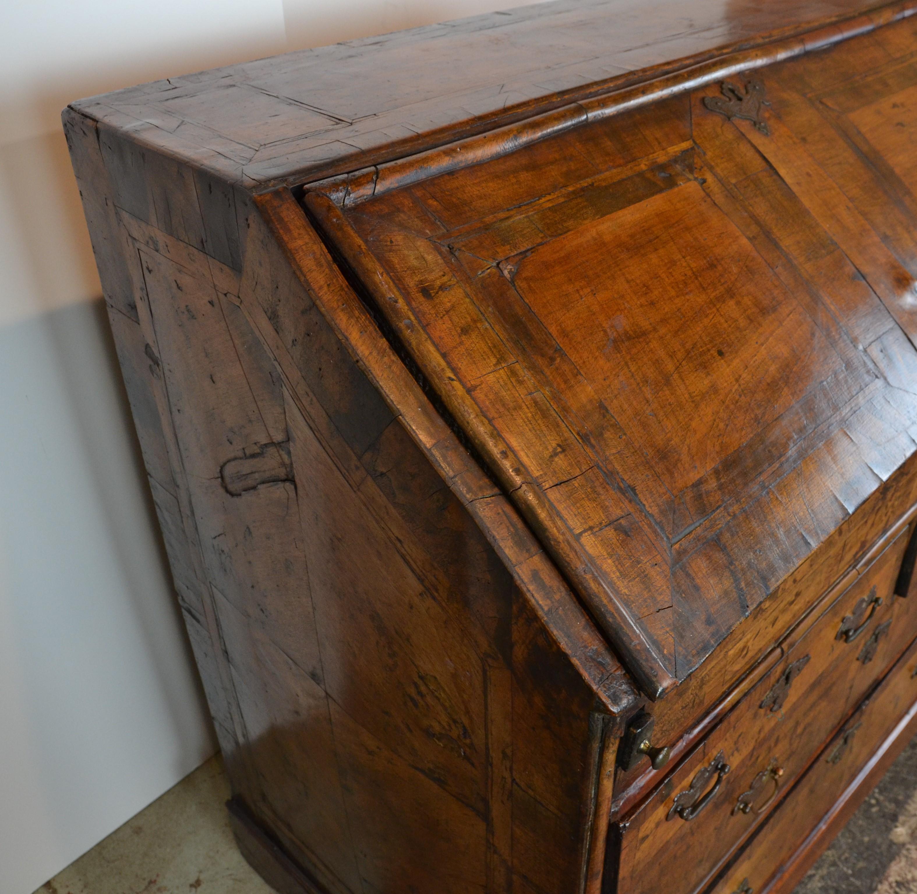 An original Queen Anne period writing desk, circa 1720. Fantastic patina on it's original walnut finish. All the good features, Quarter veneered sides. Panel design to fall front and top. Cross-banded drawers. Oak lined, 