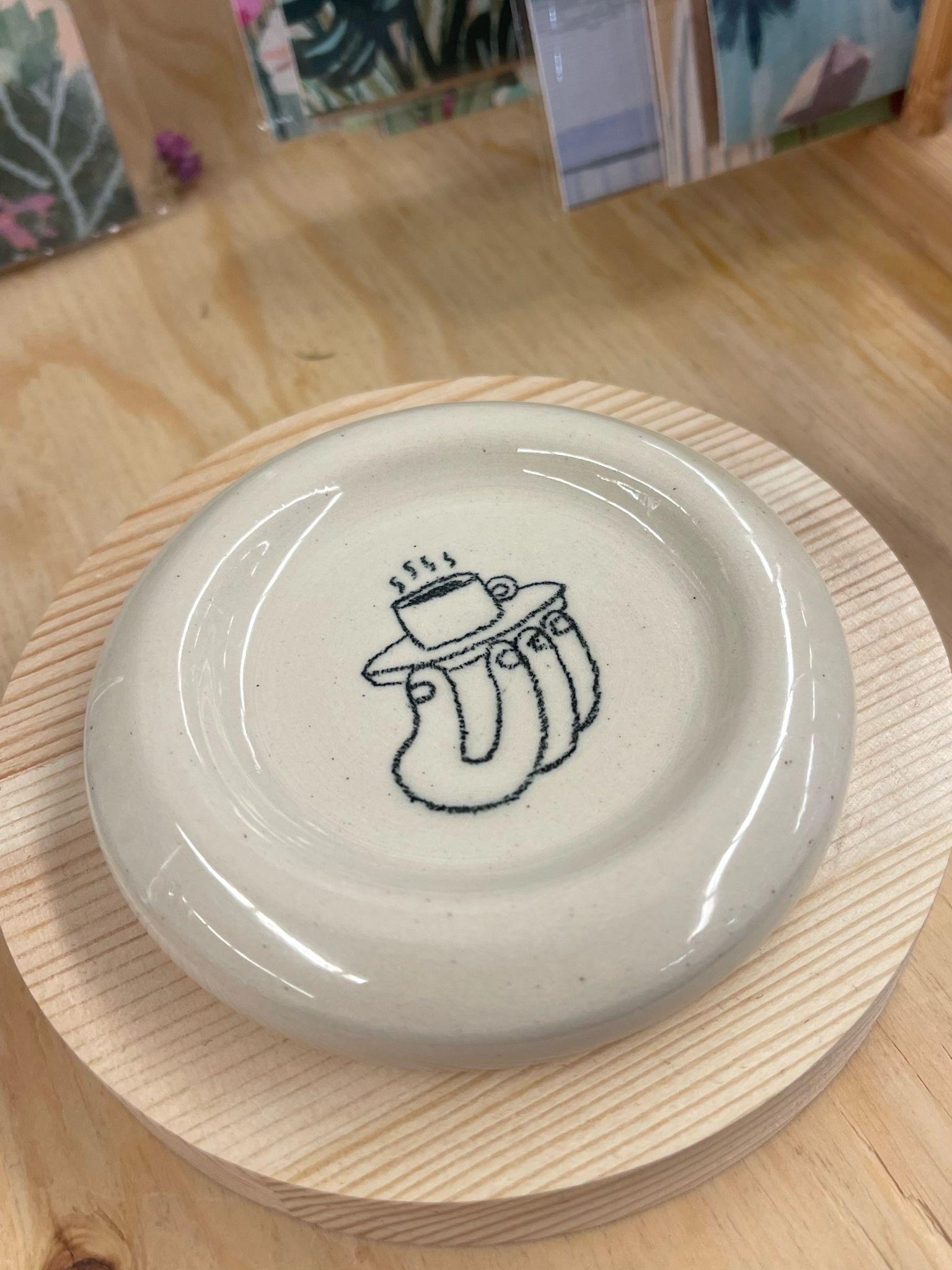 This petite dish has an adorable cartoon doodle of a hand holding Cup in the center. Makers mark on the bottom. Little Okie Studios is a Seattle company specializing in Kawaii inspired design. Every piece is Handmade, with slight variations natural