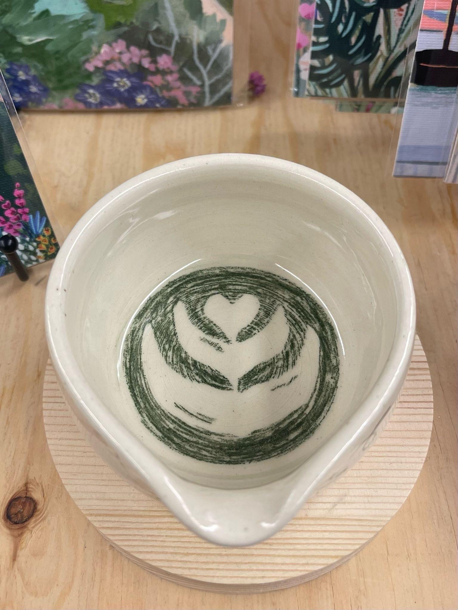 This cup has adorable doodles wrapped around the sides with handwritten “ more matcha please “. This cup has a spout for easily pouring matcha. Makers mark on the bottom. Little Okie studios is a Seattle based company specializing in Kawaii inspired