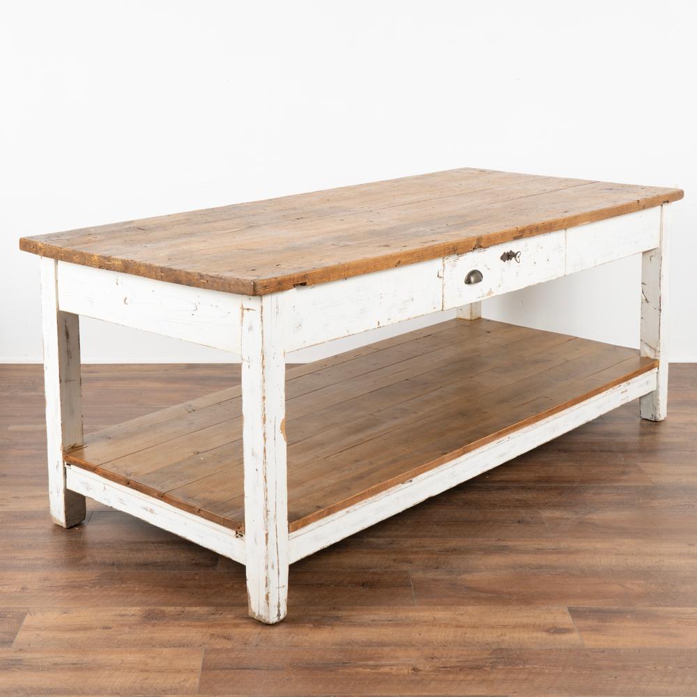 It is the years of constant use that fill this old work table with character and purpose. The white paint is original and has been distressed over many years of use.
The top and lower shelf have been left natural pine, creating a warm contrast to