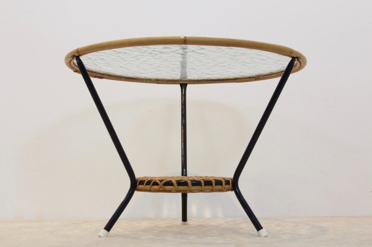 Original wicker glass round side table produced by Rohé Noordwolde in the Netherlands. The table features beautifully designed bamboo and original Glass inlay. Also featuring a lower tier with wicker bamboo and a solid black enameled frame. Very
