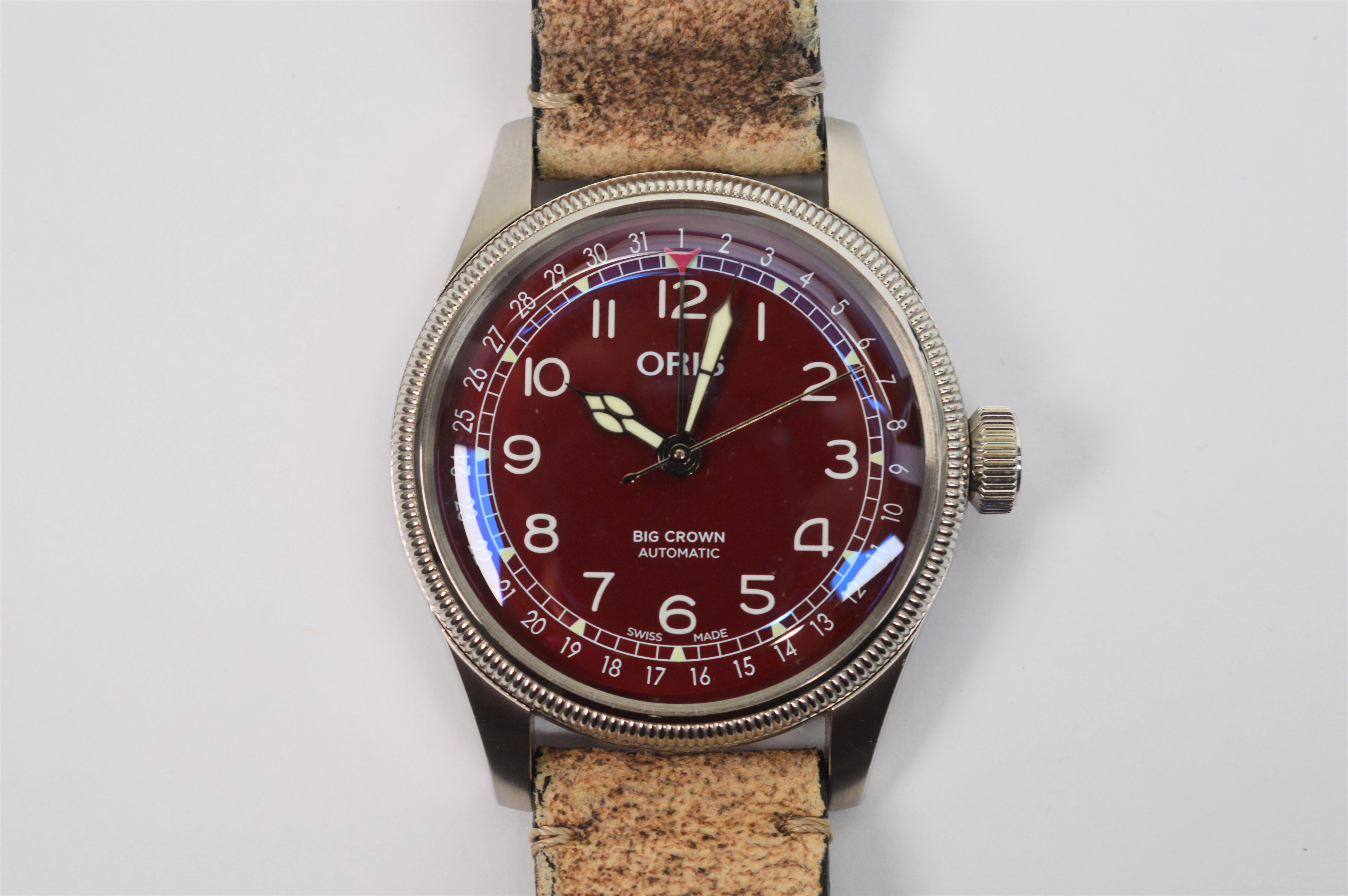 Add this impressive modern Swiss made Men's wrist watch by respected luxury mechanical watch makers, Oris Watch Co. (established in Holstein 1904) to your collection.  Bold vintage details including the deep red face and distressed leather strap