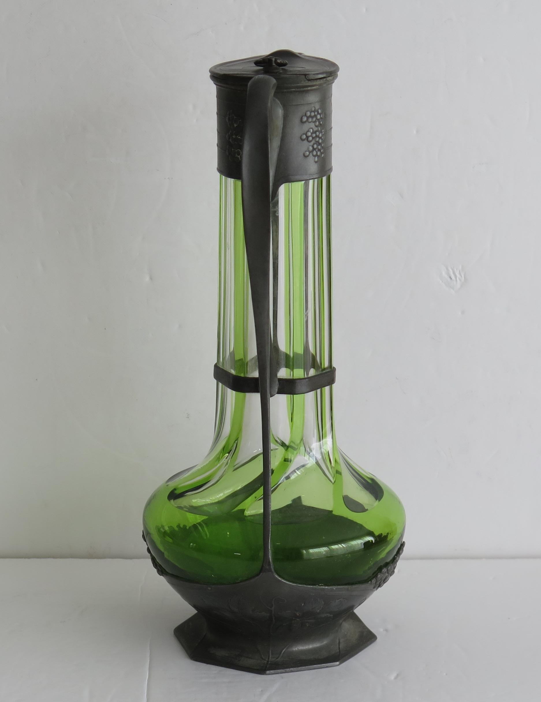 Il s'agit d'une bonne bouteille en verre vert et transparent à nervures verticales, encastrée dans un manchon en étain, le tout dans le style Art Nouveau de l'époque, fabriqué par Orivit, Allemagne, Circa 1900.

Le design et la décoration en étain