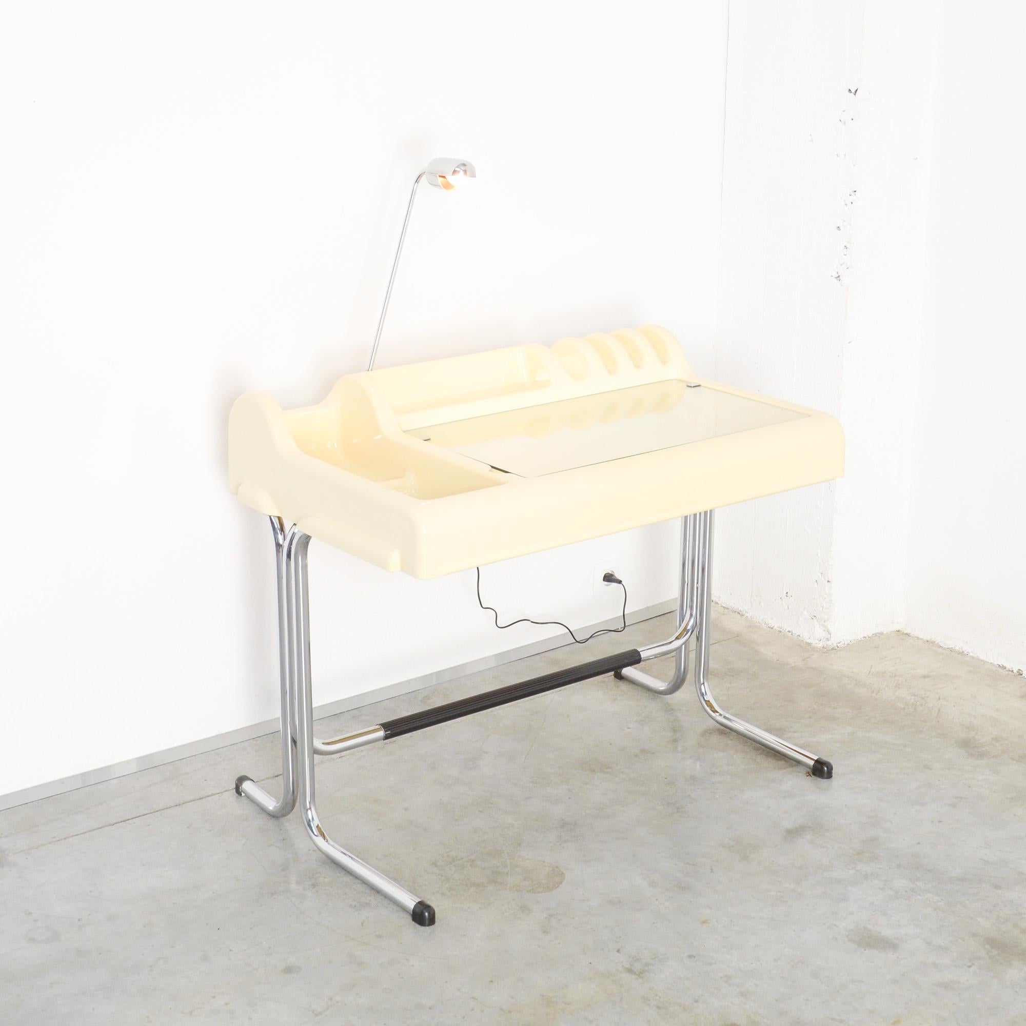 This space age desk was designed by Vittorio Parigi & Nani Prina for Molteni, Italy.
It is made of white plastic, a little yellowed due to age and use. The top is made of glass and can be opened. The chromed metal base is finished with black