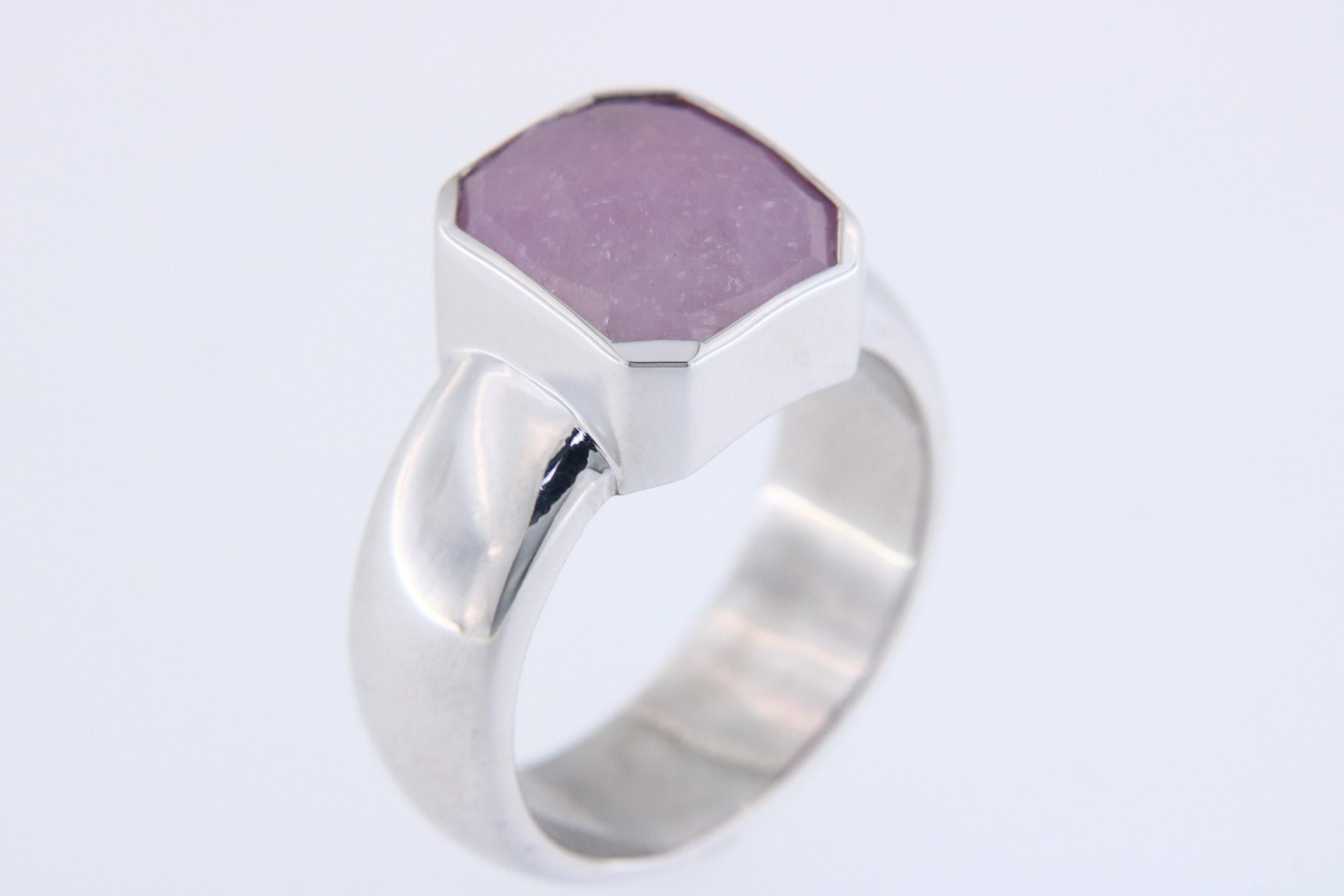 Orloff of Denmark;
This ring showcases a striking 12-carat pink sapphire, cut in a bold hexagonal shape, set atop a band of polished 925 sterling silver. The soft hue of the pink sapphire offers a touch of feminine grace, while the geometric cut