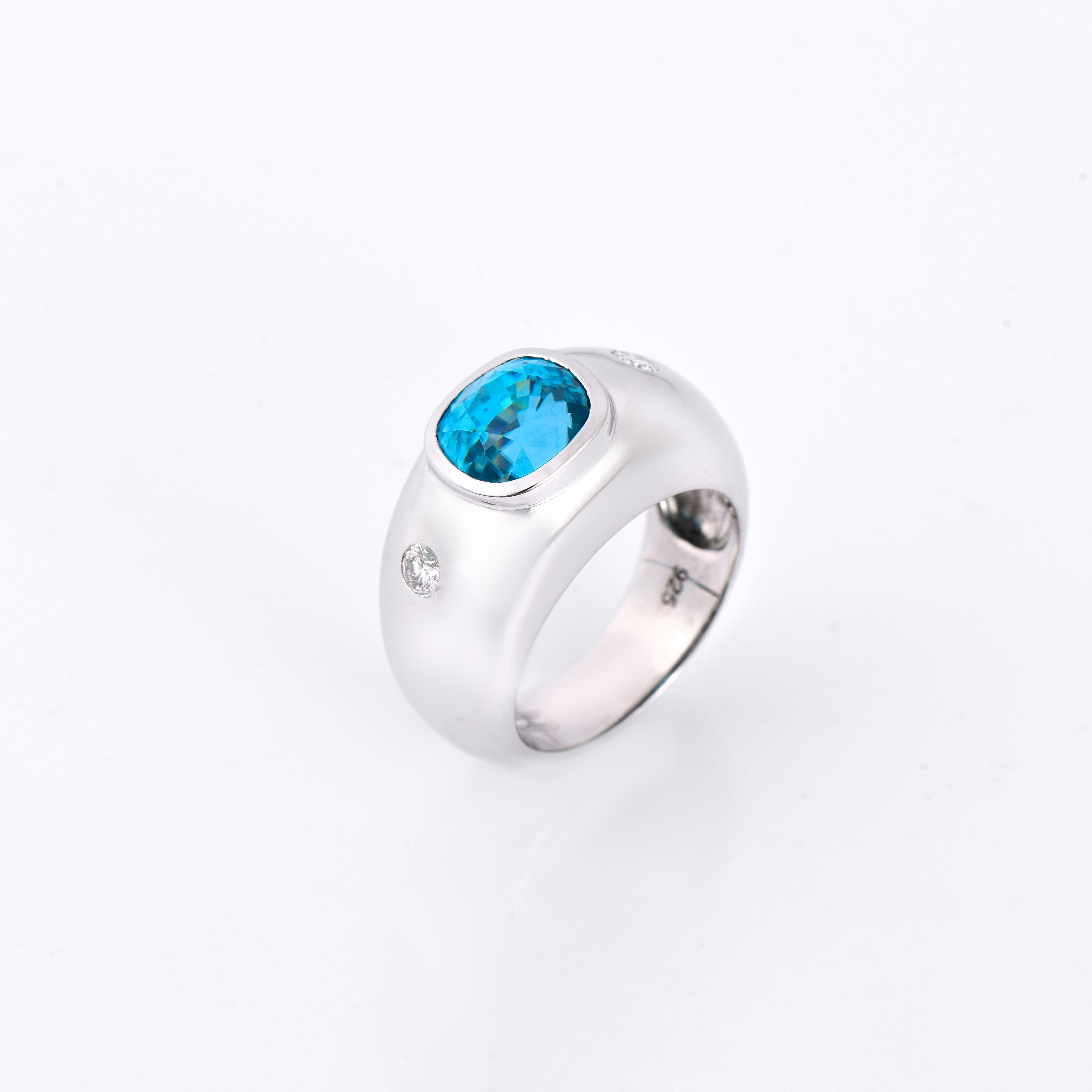 Orloff of Denmark; 925 Sterling Silver Ring set with a 7.2 carat Natural Cambodian Blue Zircon and two Natural White Diamonds.

This 925 Sterling Silver ring presents a harmonious blend of classic charm and modern design. Its smooth, rounded band is