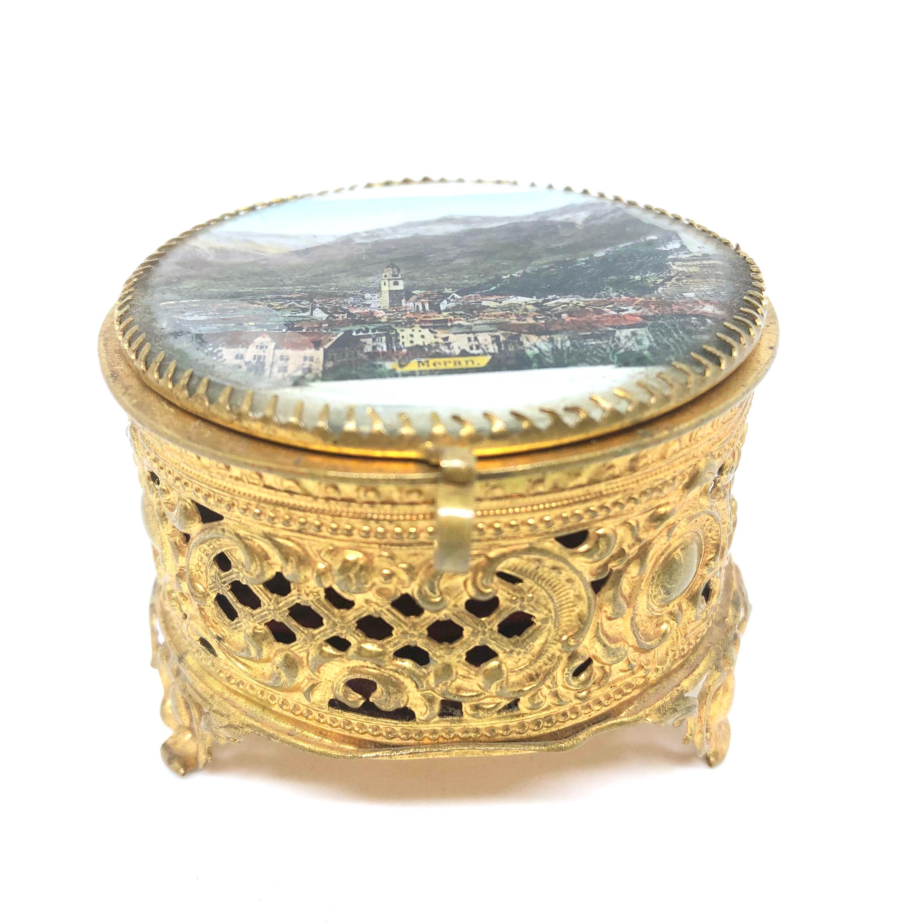 A gorgeous glass top trinket box made of ormolu. The hinged top featuring a City view of Meran. No restoration has been carried out on this charming little trinket box, which remains in very stabile and functioning condition, wear is consistent with