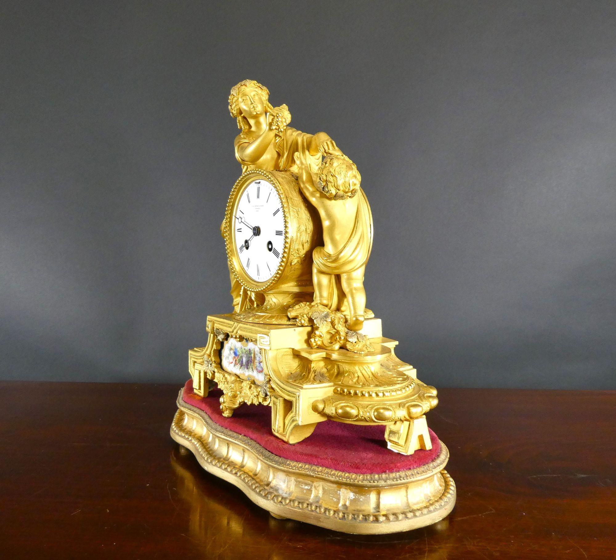 Ormolu and Porcelain Panel Mantel Clock

Ormolu figural mantel clock with beautifully cast maiden in flowing robes holding a bunch of grapes towards a cherub. Fine quality chased ormolu mounts with hand painted porcelain panel to the front. The