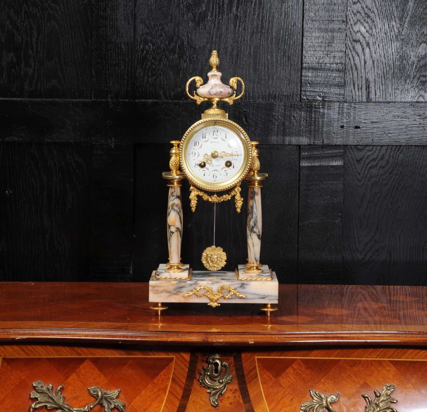 A beautiful original antique French portico clock, Louis XVI style, circa 1880. It is modelled in a stunning variegated specimen marble, salmon pink and silver blue veining, and is mounted with ormolu (finely gilded bronze). The movement is held