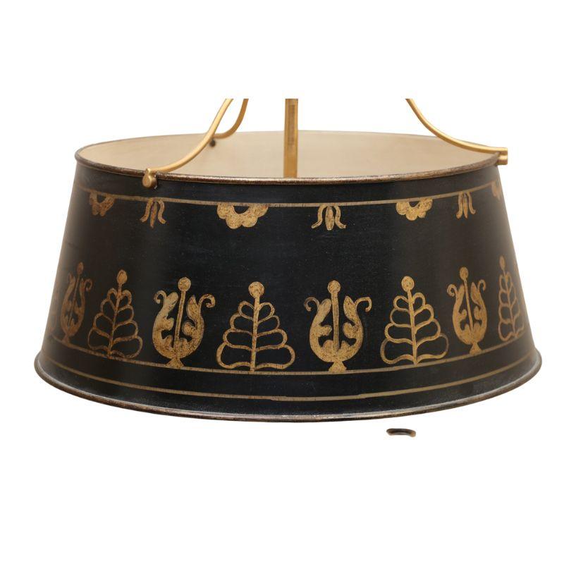Lampe bouillotte française en bronze doré et tole, à trois bras et base circulaire.  Cette magnifique lampe est dotée d'un fleuron à motif de clé avec une flèche en dessous, d'un abat-jour en tole noir décoré de feuilles d'or, de trois bras à