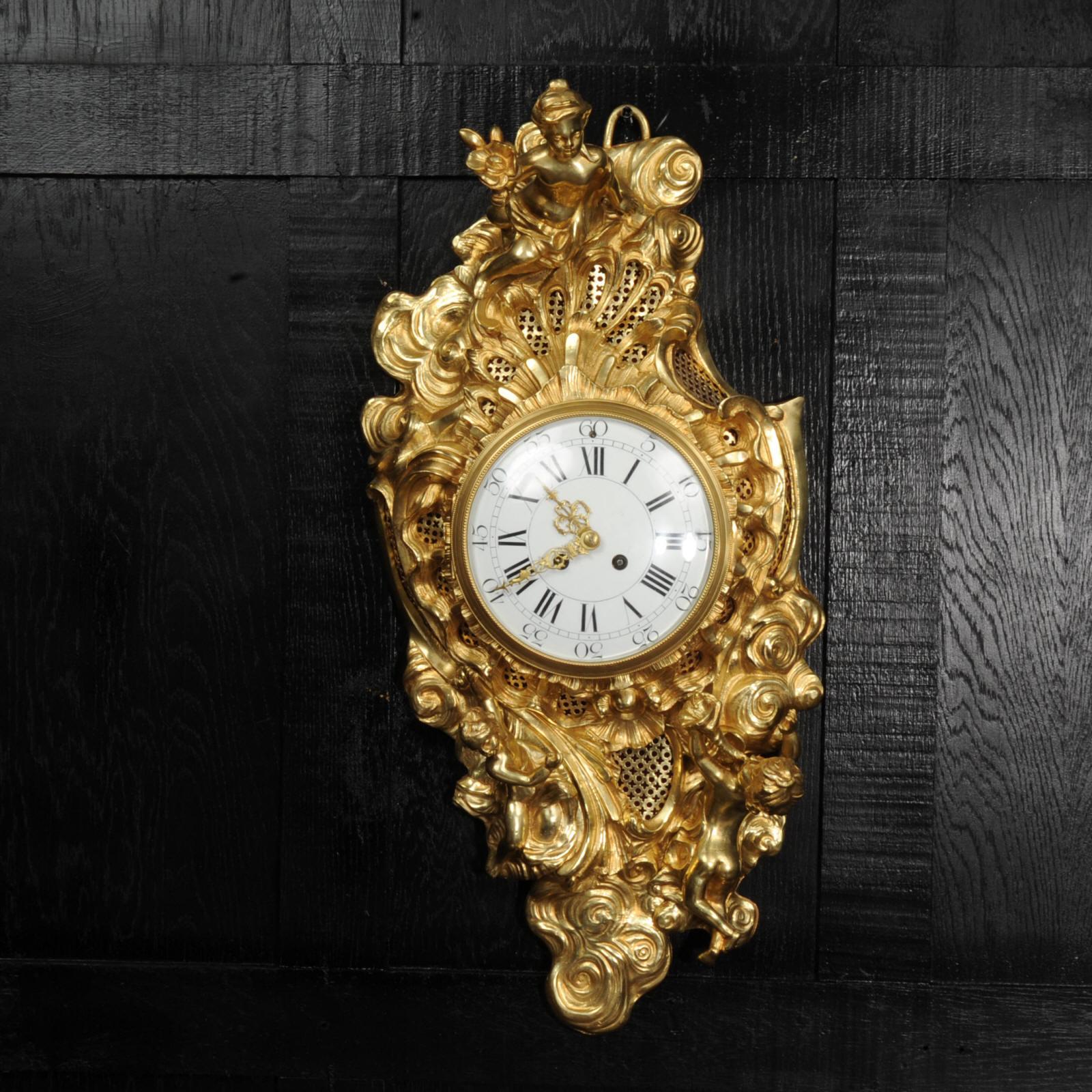 A magnificent and very large original antique French Rococo cartel wall clock. Asymmetrically modelled in the Louis XV style, the dial bursting through the swirling clouds as the sun, cherubs climbing through them, one with a bouquet, one with a