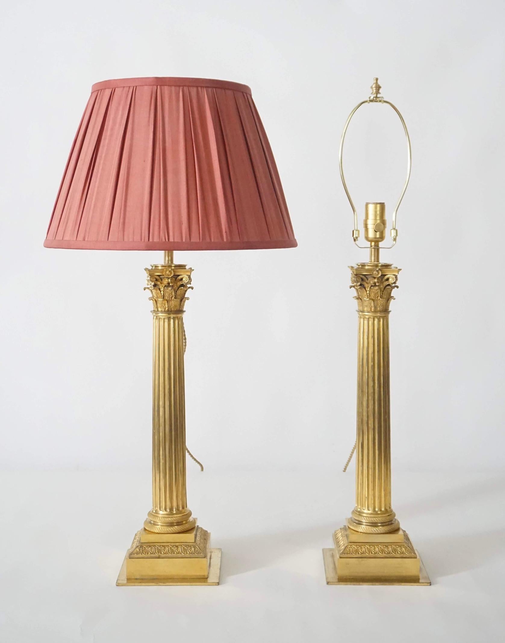 An exquisite pair of neoclassical Corinthian column form table lamps converted to electricity in the early 20th century from circa 1825 French Sinumbra oil lamp bases, the lost-wax-cast ormolu bronze capitals atop gilt-metal fluted shafts on ormolu