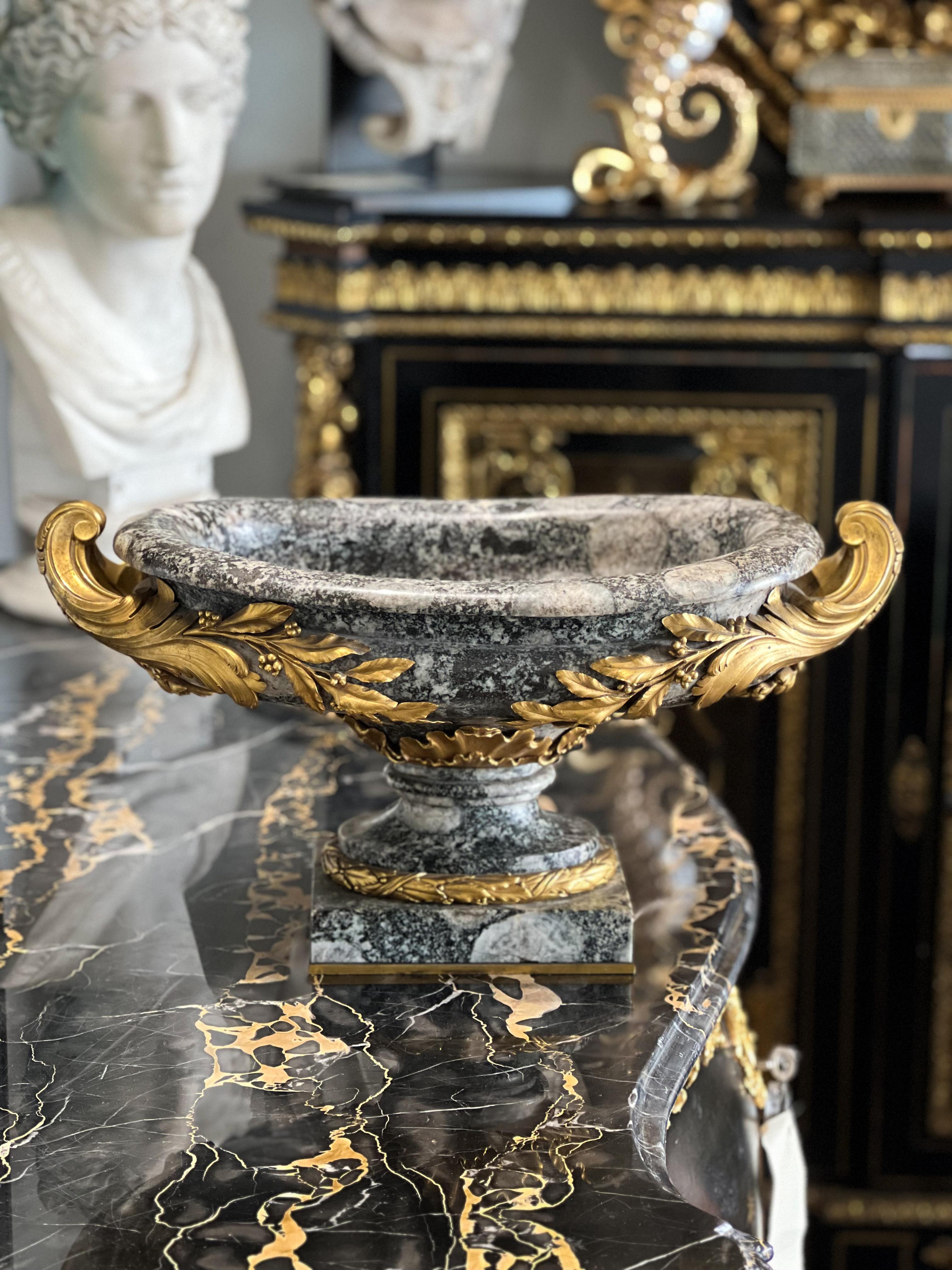 A FRENCH ORMOLU-MOUNTED CORSITE NAPOLÉONITE CENTERPIECE
BY François Linke, PARIS, LATE 19TH/EARLY 20TH CENTURY
The Dual-handled ovoid basin raised on a rectangular foot with a laurel-cast border.
9 in. (23 cm.) high, 17 ¼ in. (44.5 cm.) wide

The