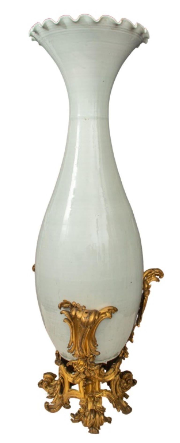 Belle Epoque ormolu-mounted Japanese palace vase in monochromatic white glazed porcelain, of elongated trumpet form with ruffled flaring rim above a long neck, the mount in the Louis XV style and composed of three palm-cast rocaille supports