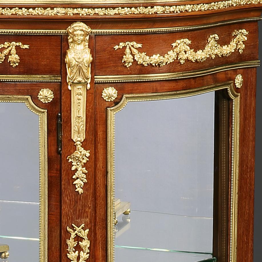 A French ormolu-mounted mahogany vitrine
firmly attributed to François Linke, Paris.

Of demilune outline, constructed in mahogany, with gilt bronze mounts, in the Louis XVI Transitional style, rising from scroll and acanthus cast sabots, with