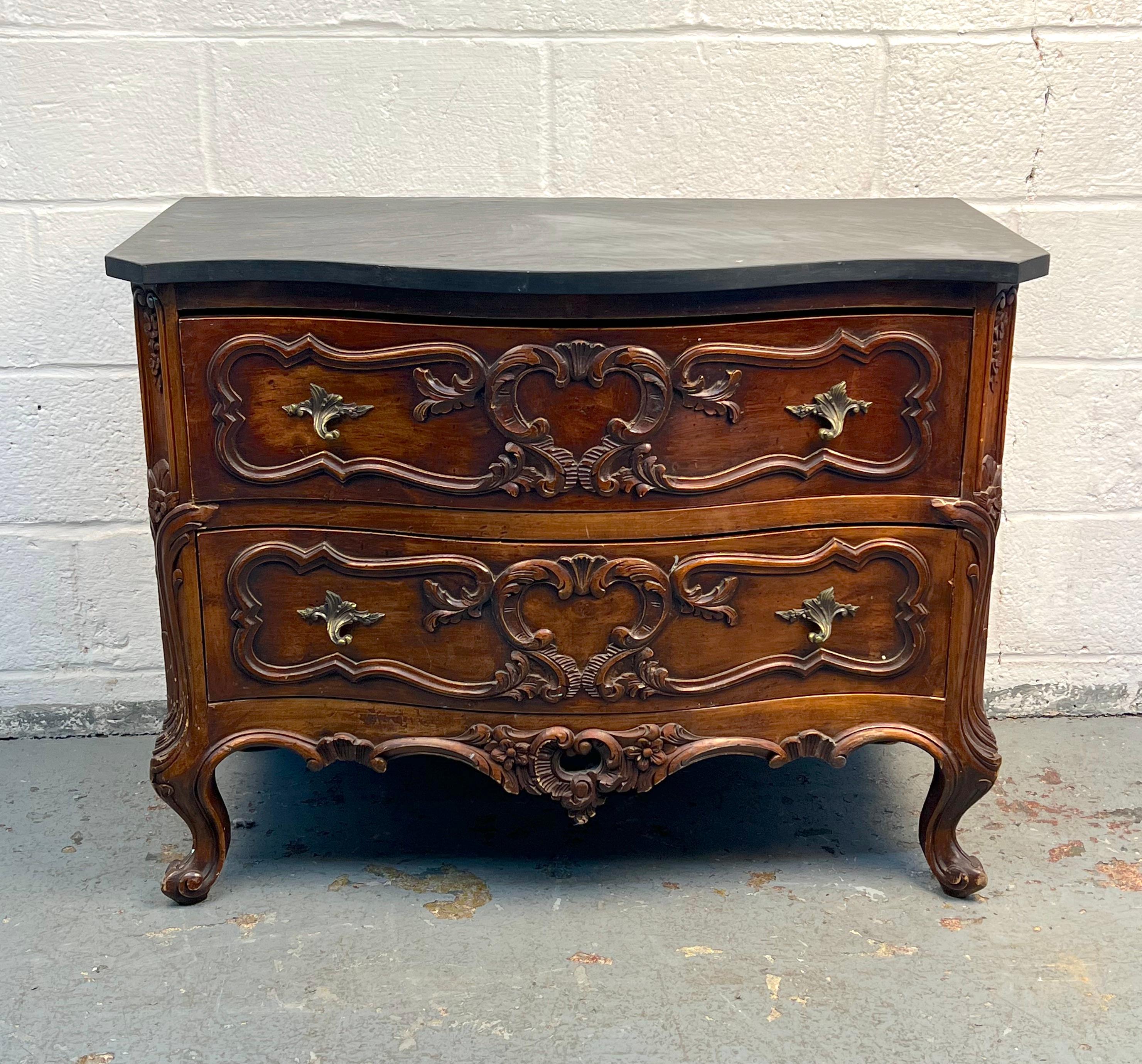 Comò distintivo in stile Chippendale con dettagli ornamentali e una raffinata struttura in noce, sormontata da un'elegante superficie in ardesia. La combinazione di artigianato decorativo e materiali resistenti rende questo pezzo funzionale ed
