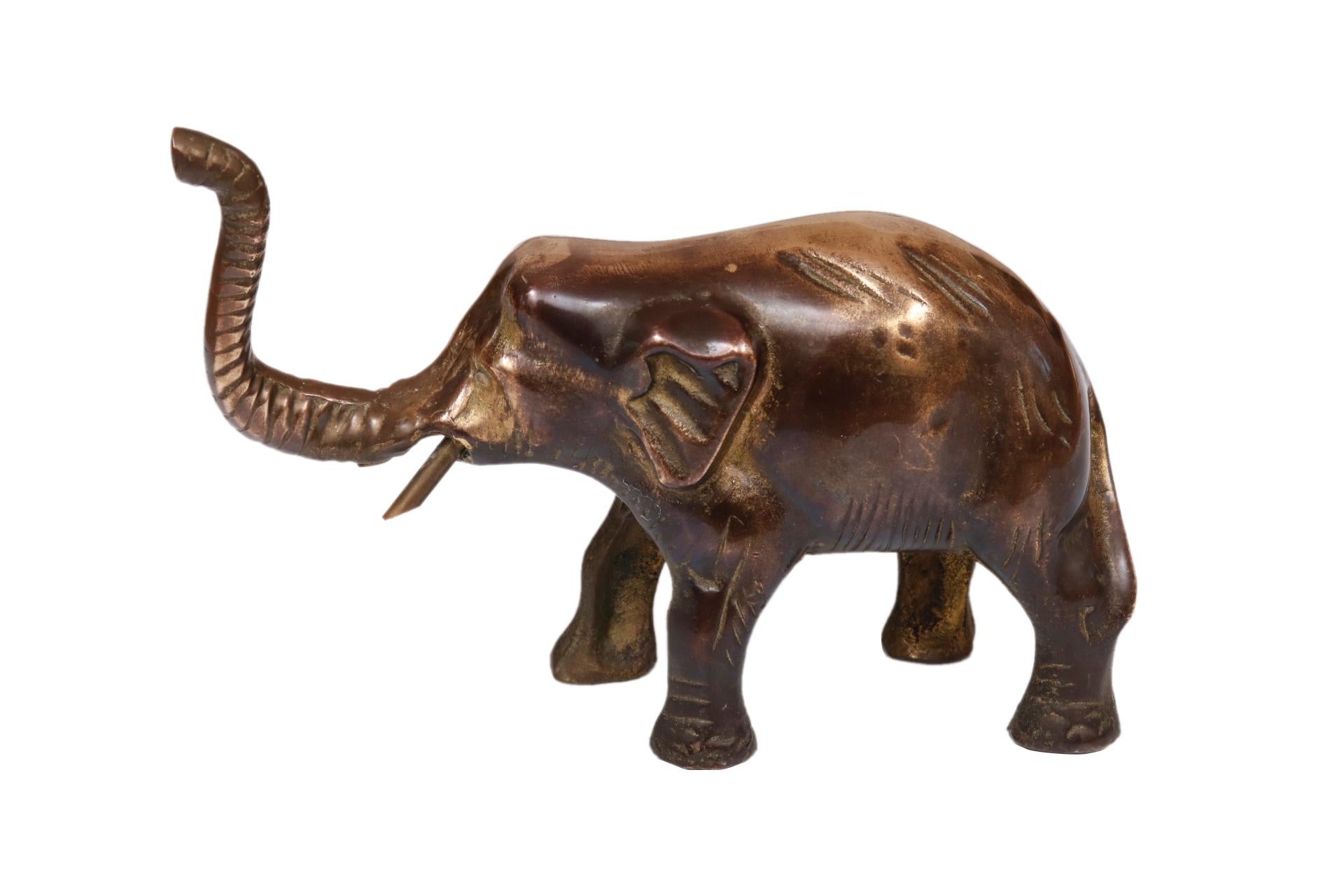 An ornamental bronze figure in the shape of an Indian elephant. Cast with an upraised nose and tusks. Finished with line details to define the eyes, small ears and tail.