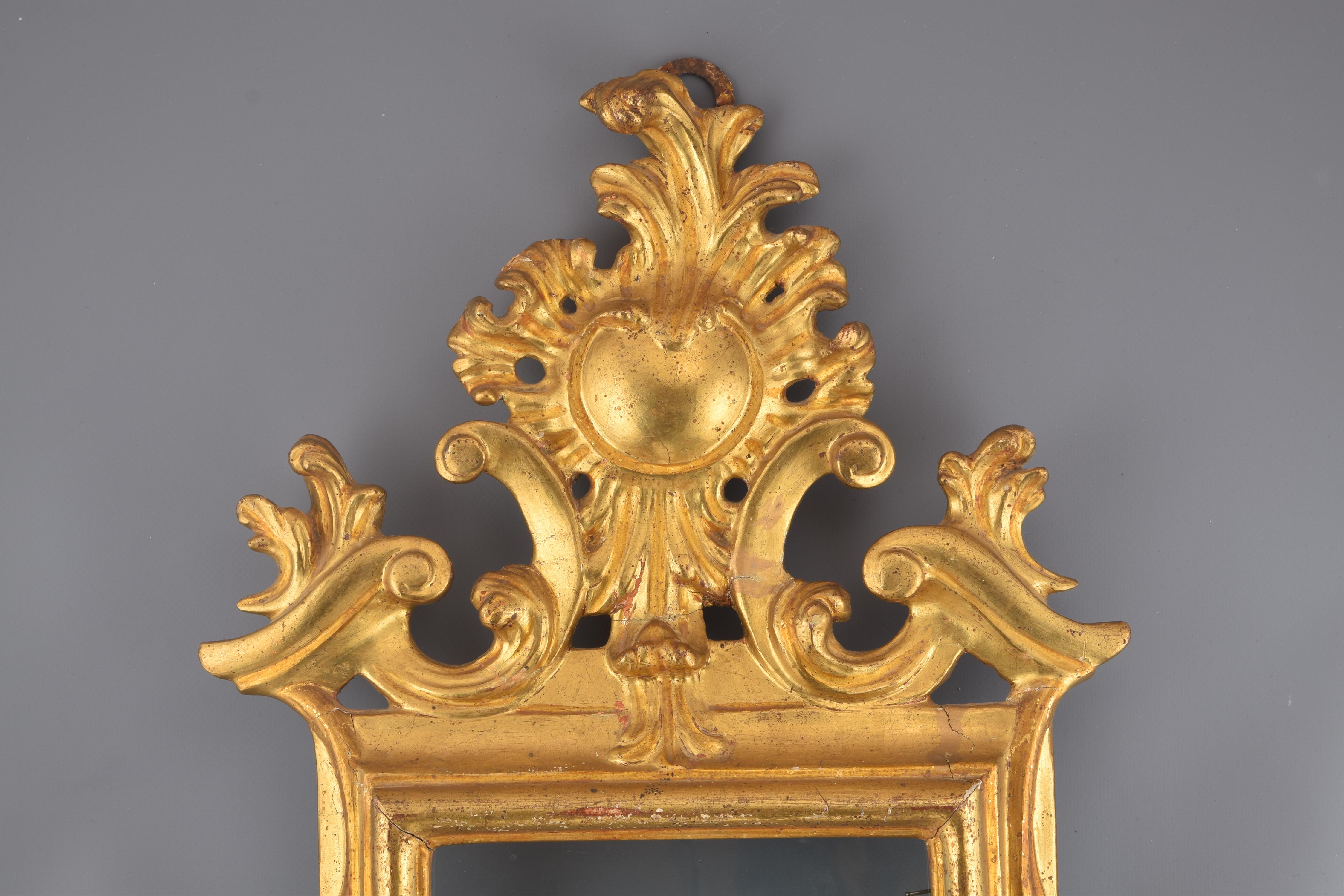 It requires restoration.
Rectangular cornucopia with carved and gilded wooden frame decorated with a series of smooth moldings and with a very elaborate finish on the upper part (arranged in symmetrical composition, architectural and vegetal