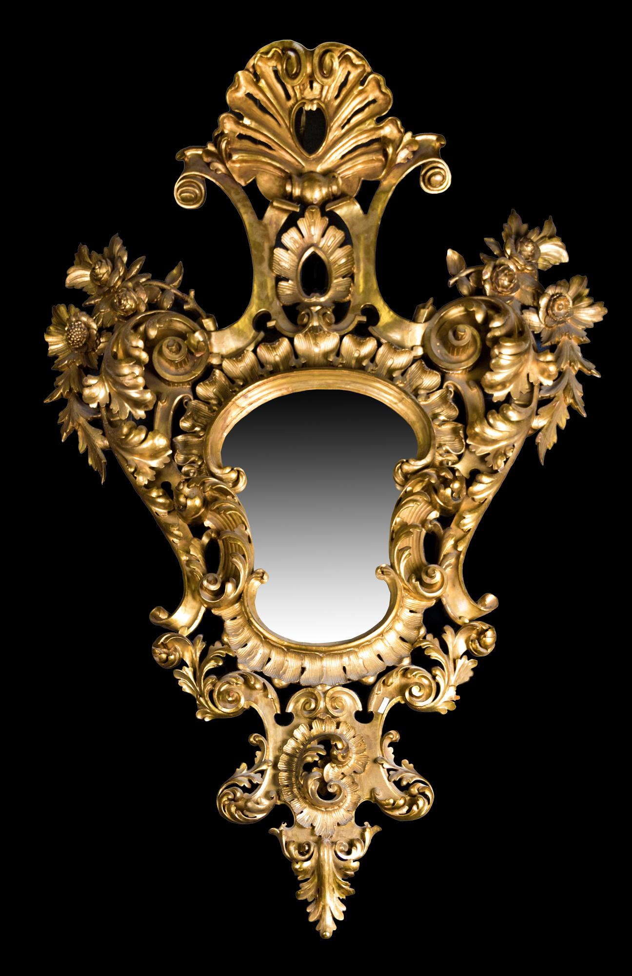 Ornamental mirror made in gilded wood decorated with an elaborate composition around a central space, reserved for the mirror. From the inside out, the decoration, with accentuated chiaroscuro, shows curved shapes that recall those from the 18th