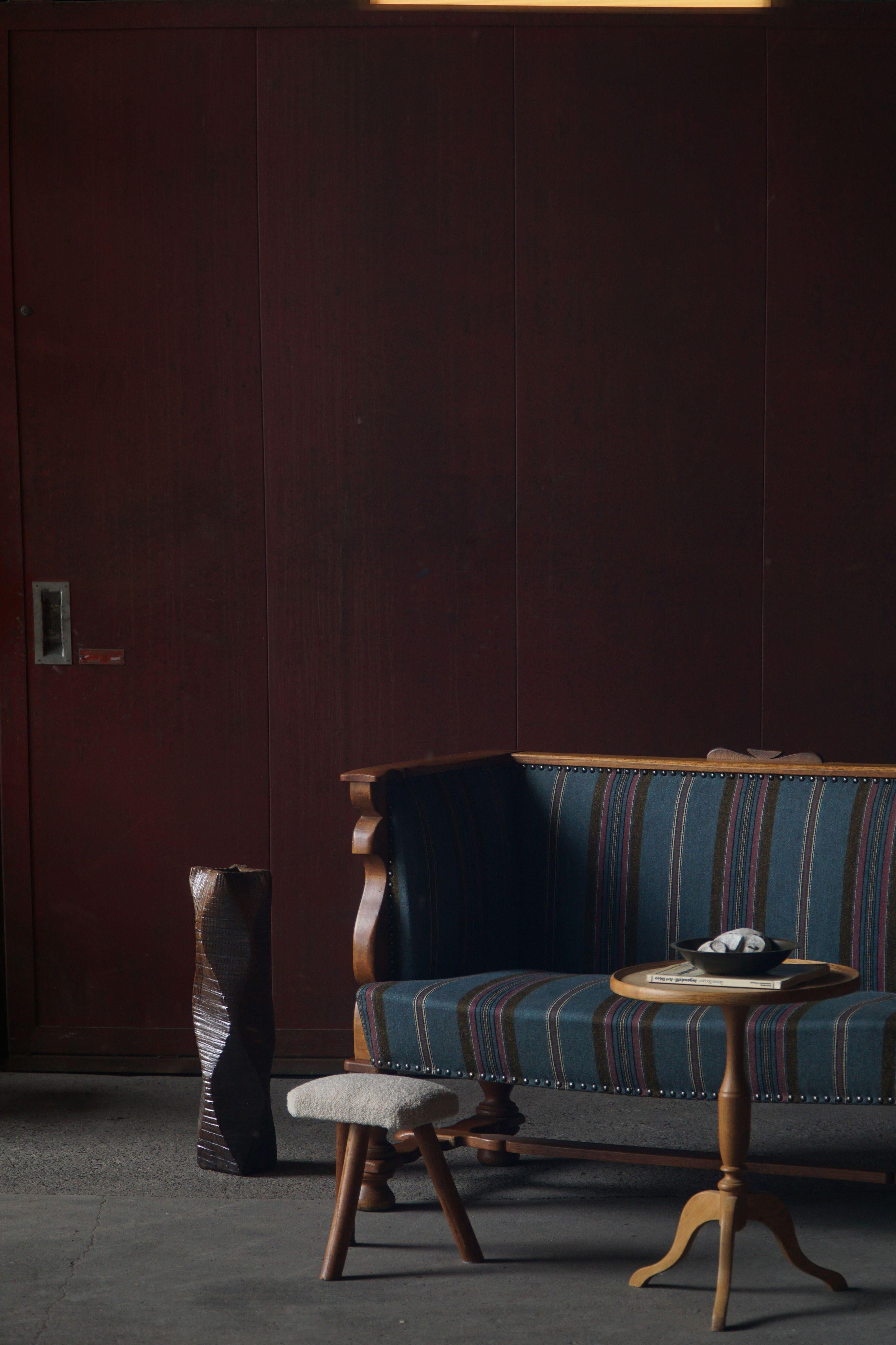 A distinguished Swedish sofa from the 1930s, this piece features a solid oak frame with ornate carving along the backrest and arms—seamlessly marrying refined detail with structural clarity. What makes this iteration uniquely captivating is the