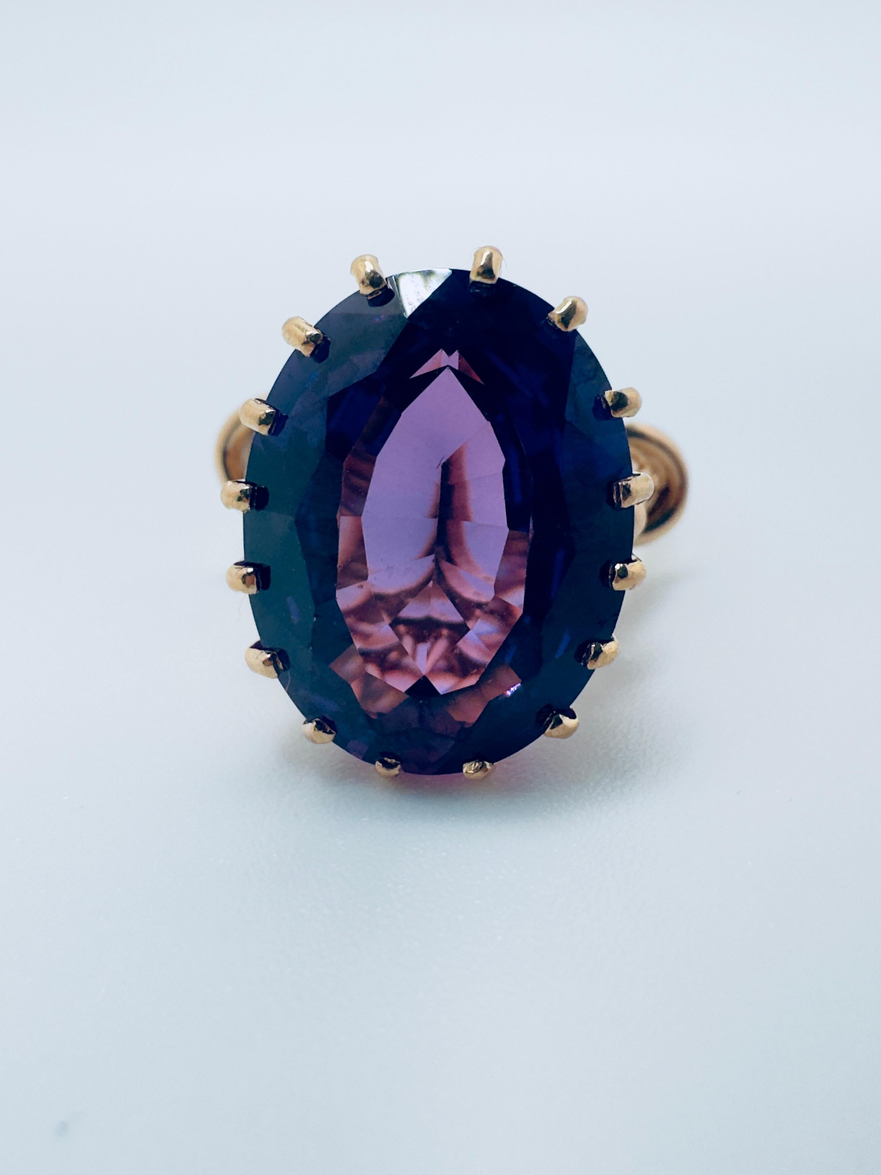 Cette bague remarquable est réalisée en or jaune 18 carats et met en valeur une alexandrite synthétique captivante comme pièce maîtresse. La pierre ovale à facettes mesure 16x2 et pèse 9,52 carats. Elle présente une brillance et une couleur