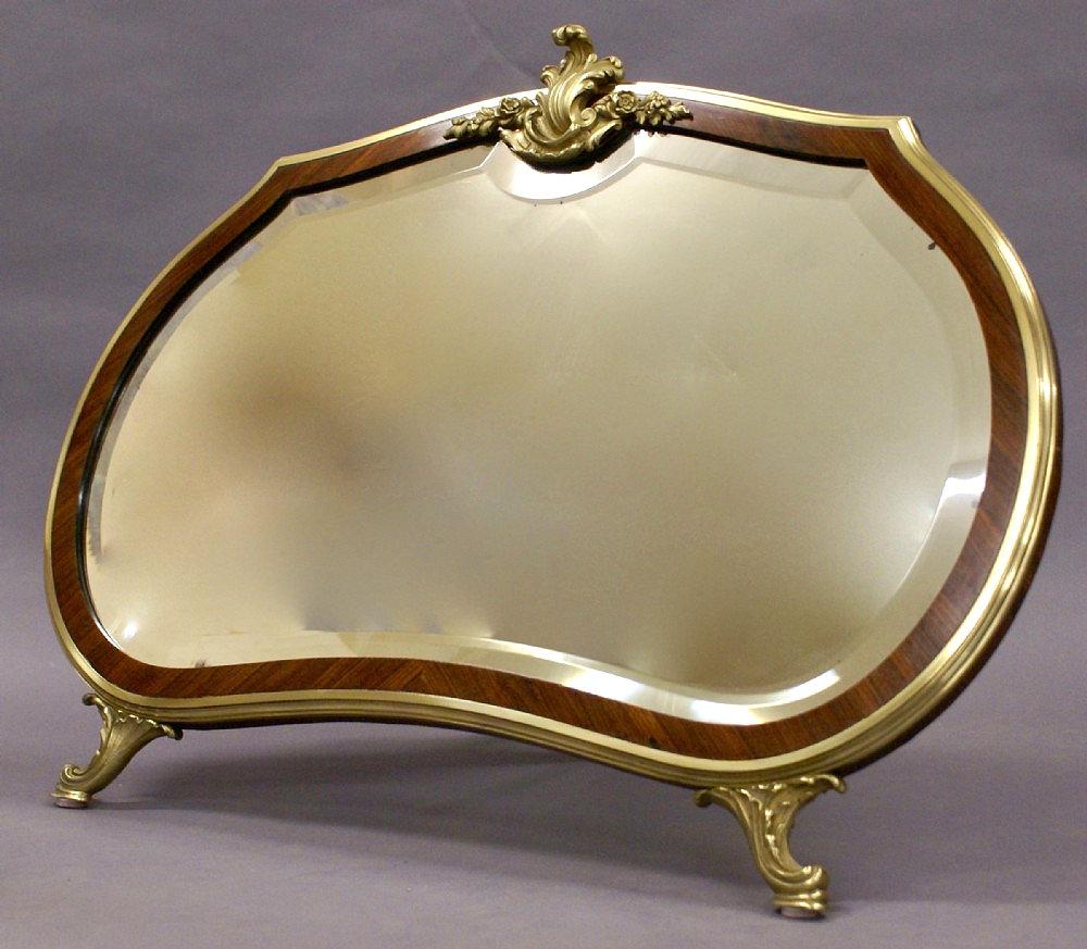 This splendid and well-proportioned French King Wood and ormolu dressing table mirror features a gracefully shaped beveled mirror surrounded with an inner border of rosewood and finished with an ormolu trim standing on 2 ornate front feet and a