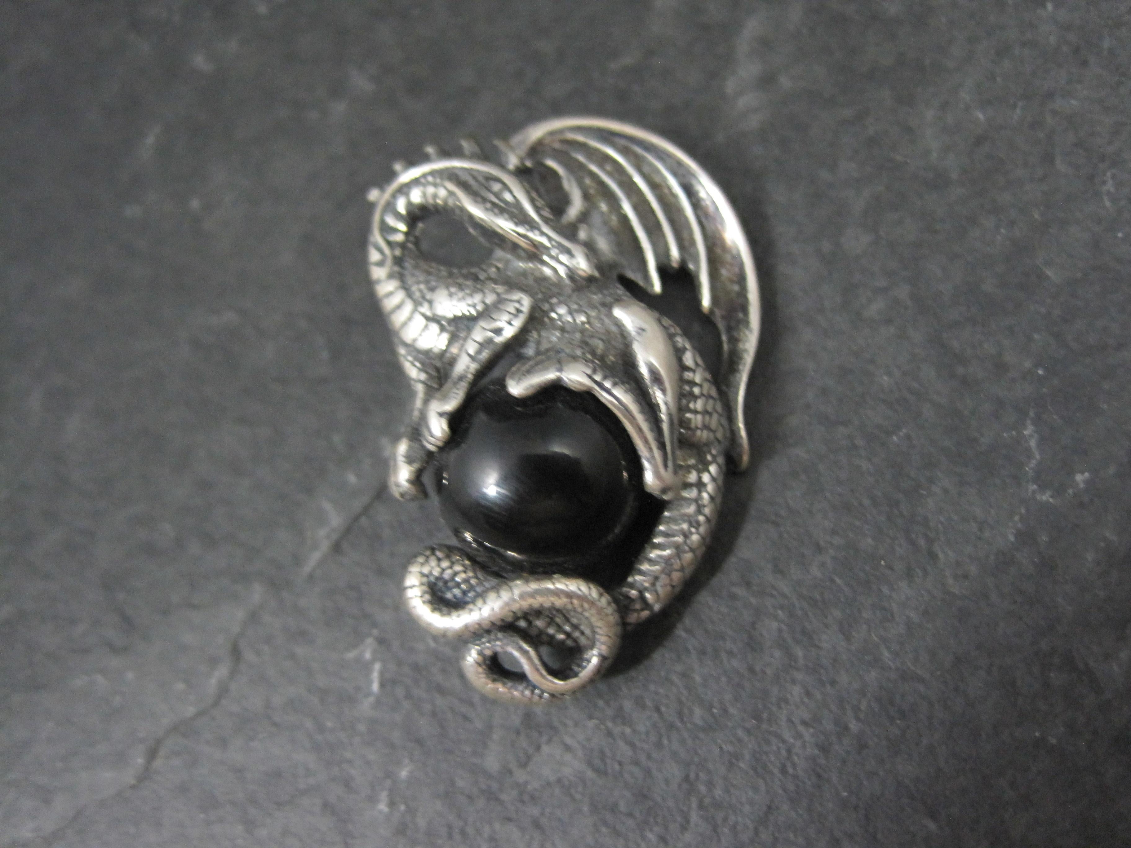 Questo splendido ciondolo a forma di drago immobiliare è in argento sterling con una sfera di onice nera di 12 mm.

Misure: 7/8 per 1 3/8 pollici

Punzoni: AICC, 96, 925

Condizioni: Eccellente