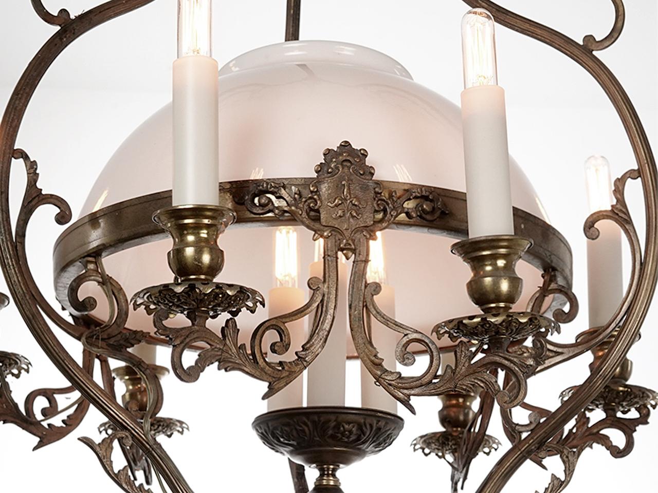 This early glass candle chandelier has a nice rich look. Its complete with its milk glass dome and glass tube candles. The finish is untouched and came out of a small 1920s New York lobby. it takes 9 25W candelabra bulbs or LEDS. Its 30 inches plus