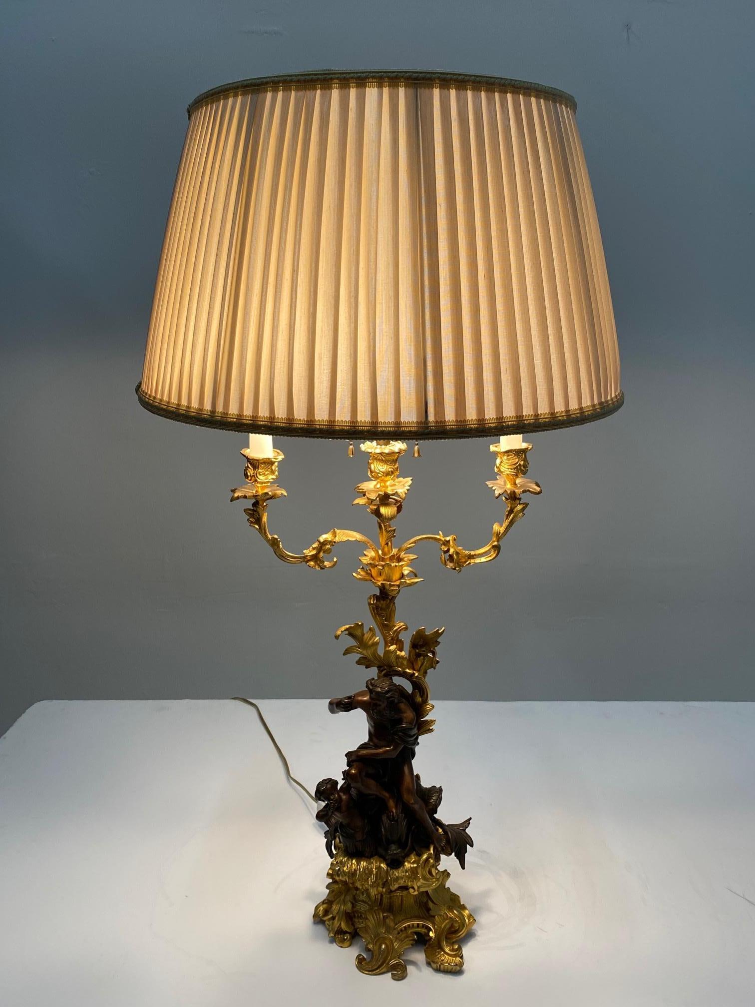 A true work of art in a very ornate French 19th century gilt & patinated bronze candlestick turned into a table lamp, depicting a sculpture of Neptune riding a dolphin with a putti companion by his side.
Note: Shade not included.