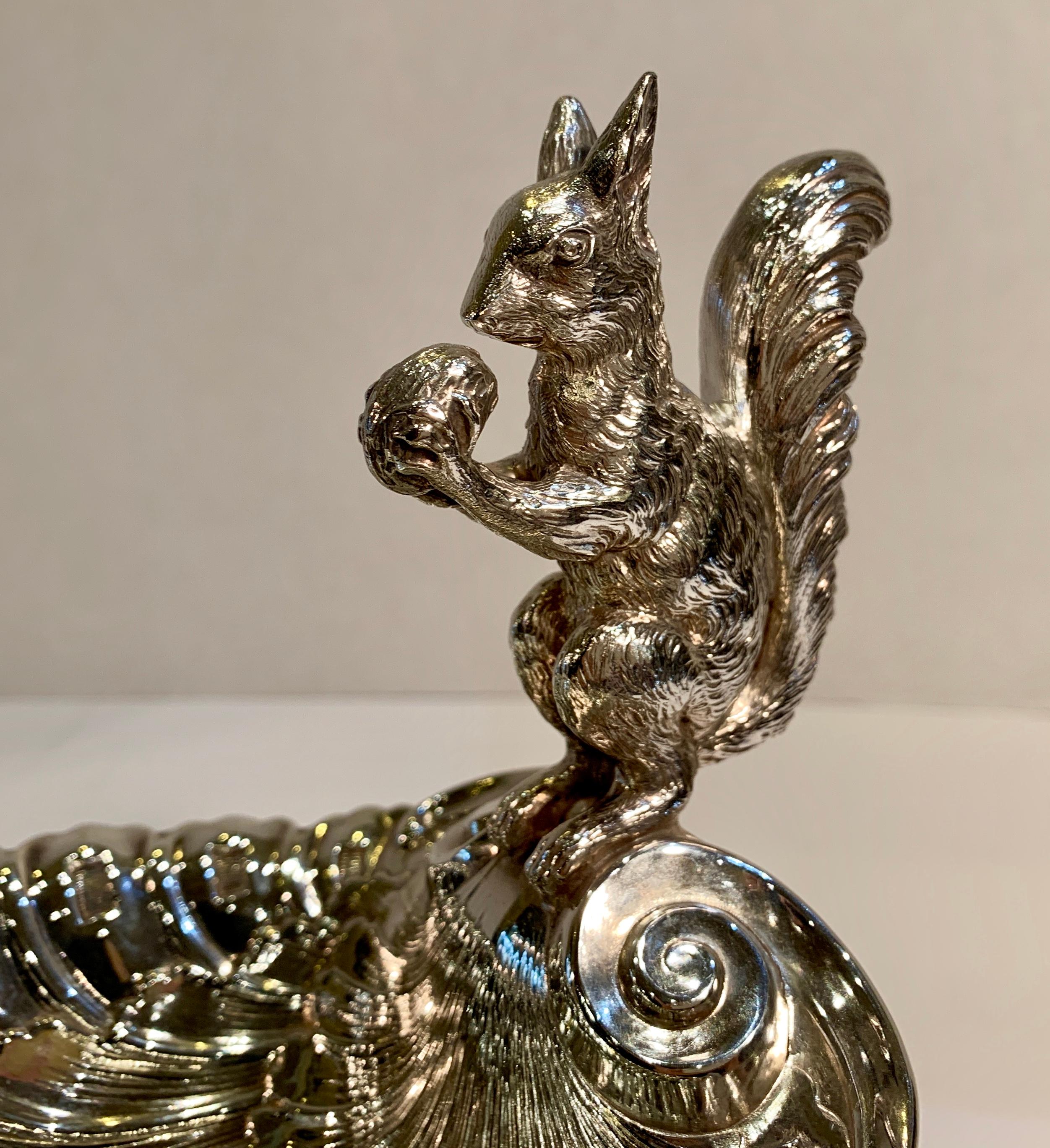 Beautiful hand made antique Victorian era ornate silver compote features a squirrel holding a nut perched on the top back edge of the very fancy and detailed shell shaped scalloping bowl. The bowl is attached to a footed pedestal which has an
