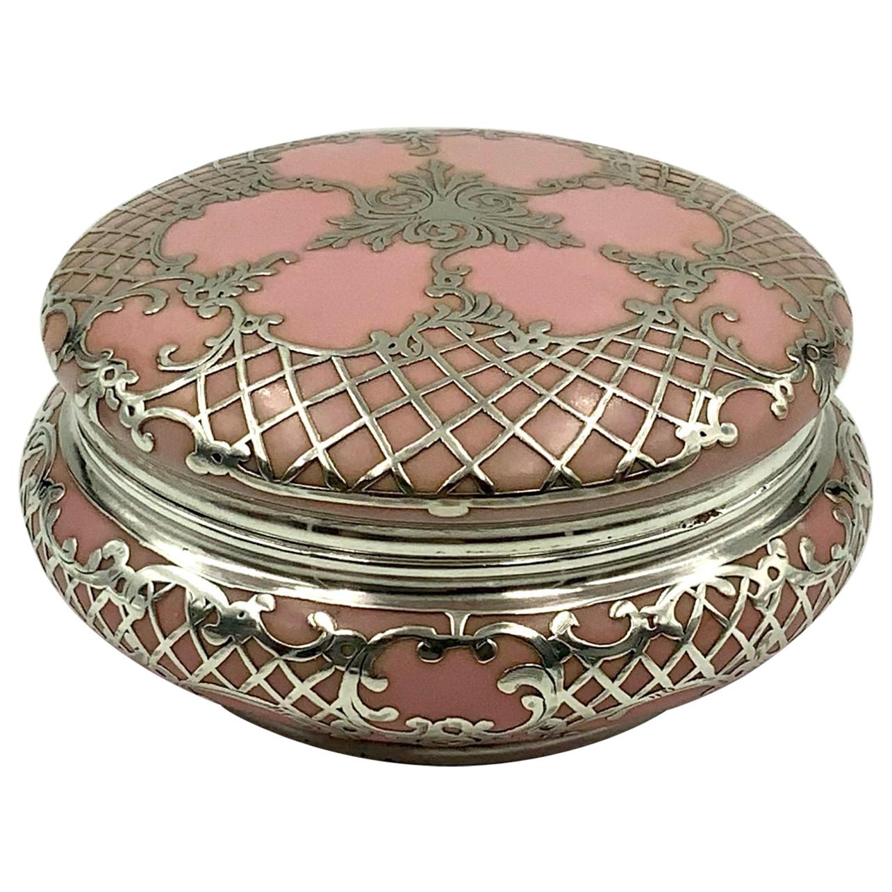 Gorgeous trinket box or powder jar featuring an ornate scroll and lattice design sterling silver overlay over a pretty pink porcelain. The mark on the bottom is not legible.